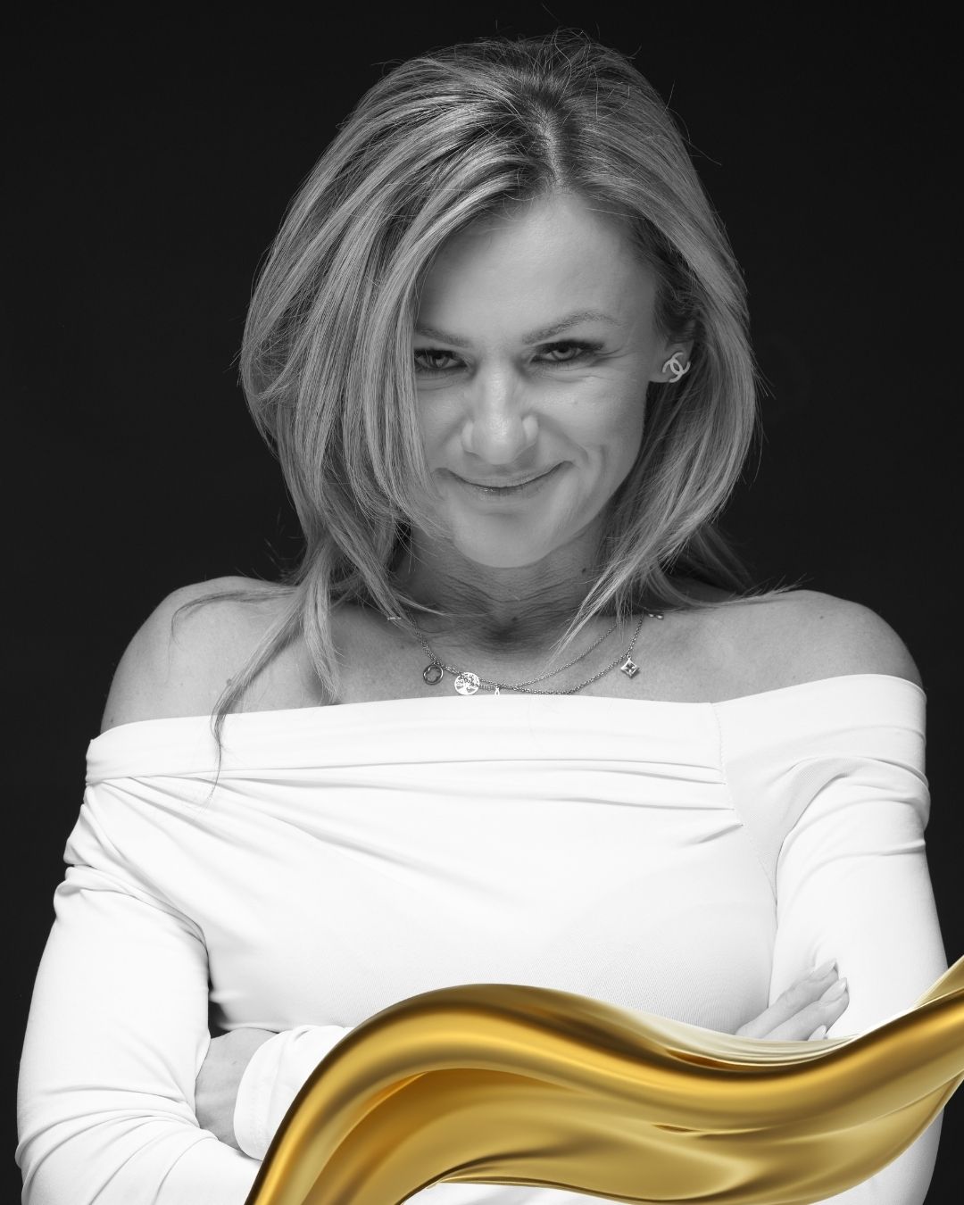 Schwarzweiß-Porträt einer eleganten Frau mit verschränkten Armen vor dunklem Hintergrund