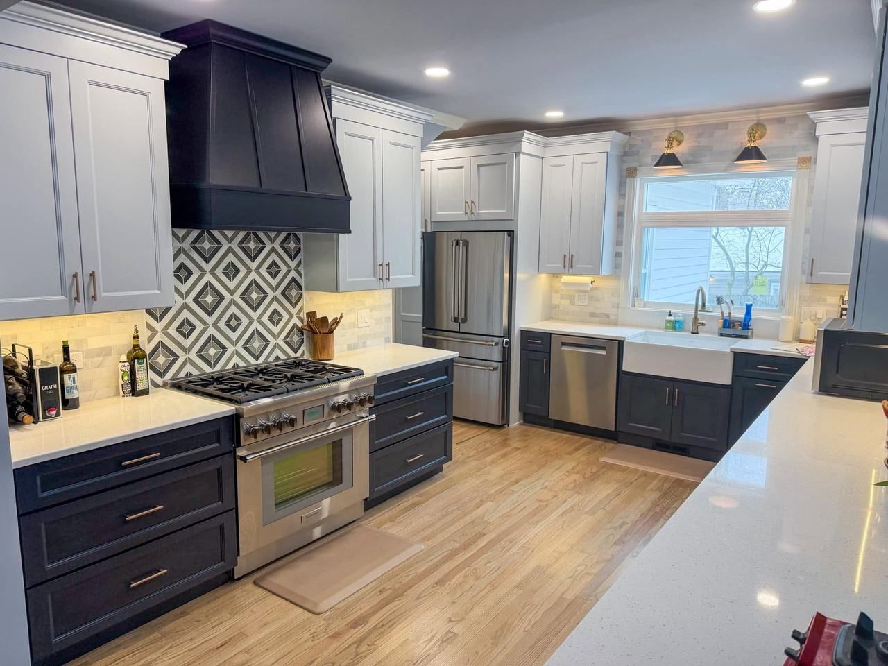 Remodeled kitchen with navy lower cabinets, white upper cabinets, a dark navy range hood and a patterned diamond tile backsplash