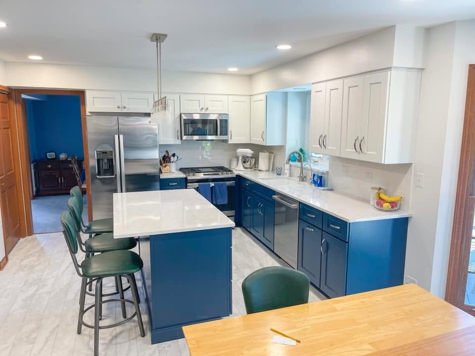 Kitchen with blue lower cabinets and a blue island, white shaker upper cabinets and white countertops