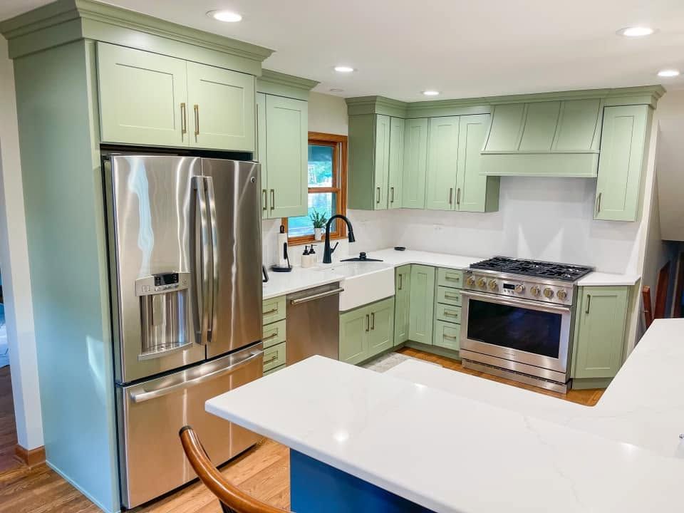Sage green shaker cabinets with crown molding, a matching range hood and a white farmhouse sink