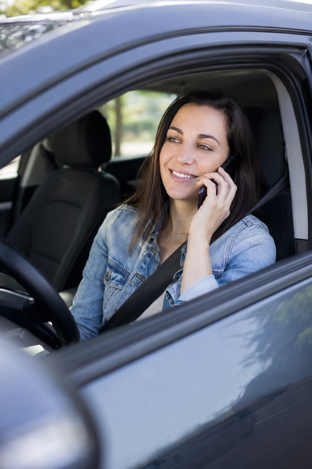 Relieved auto repair customer sitting in a parked car and talking on the phone