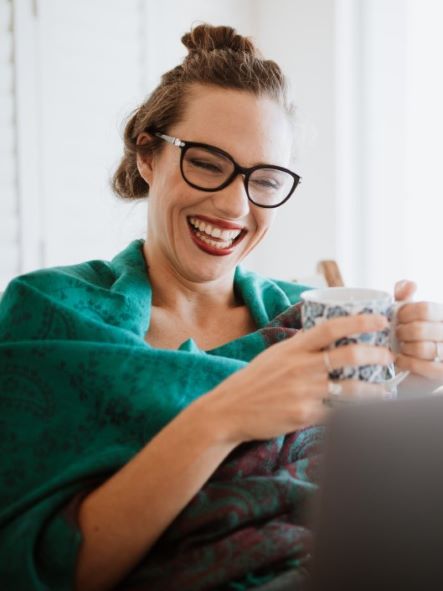 smiling white woman with glasses holding a cup of coffee