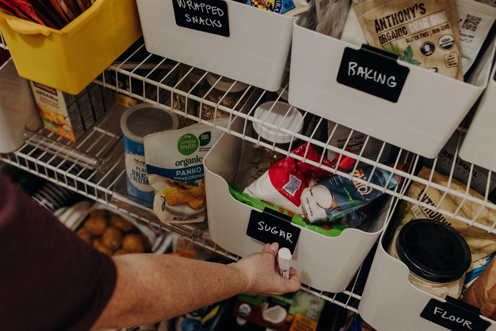 katie, putting a label on a bin in a pantry katie, putting a label on a bin in a pantry
