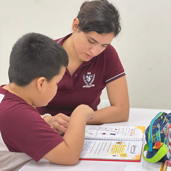 Profesora acompañando a un estudiante mientras revisa su trabajo