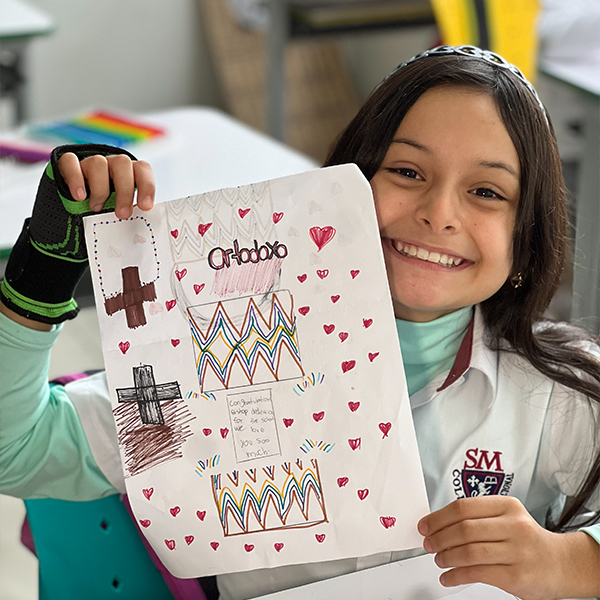 Estudiante mostrando un trabajo de arte hecho en clase