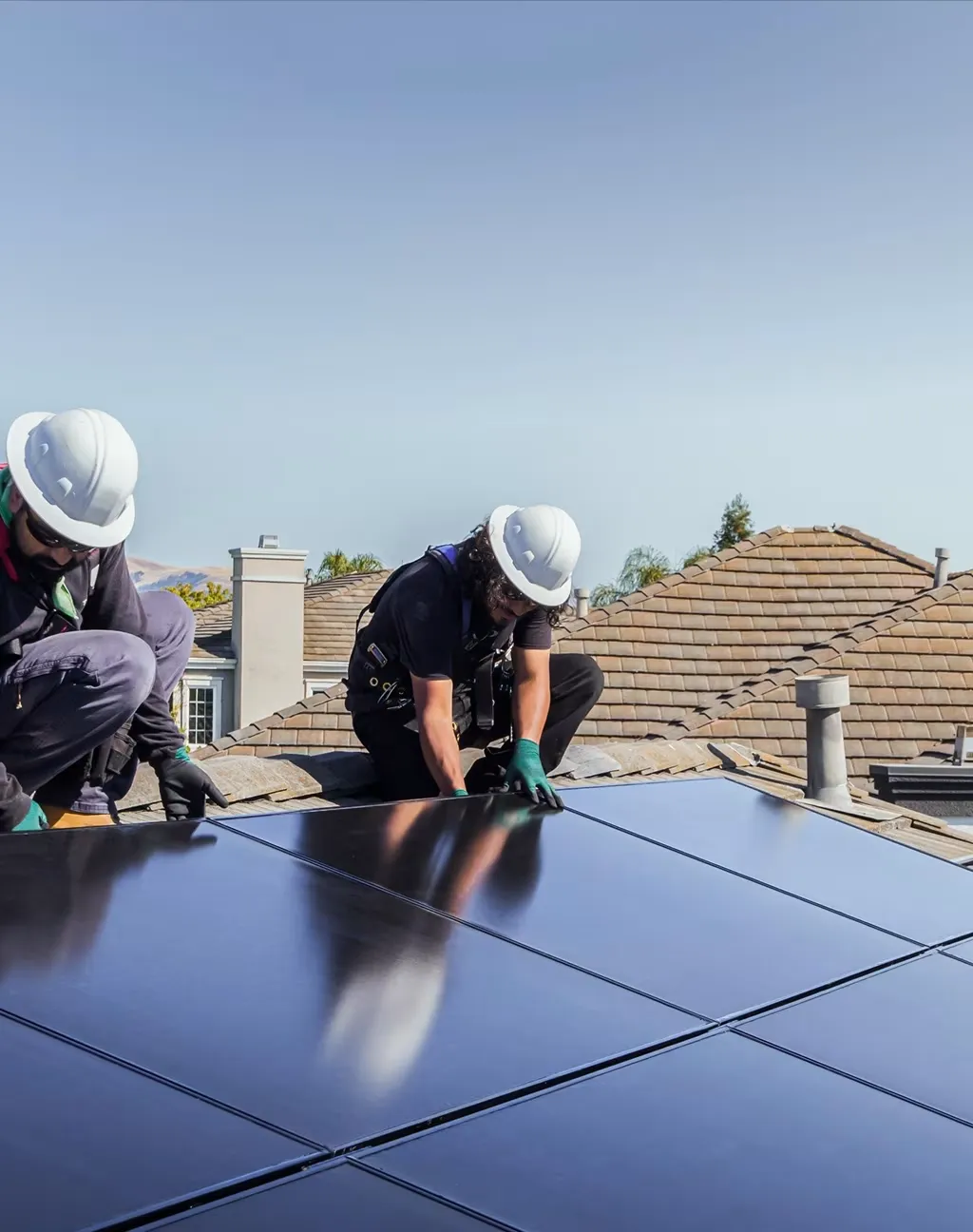 Technicians installing solar panels on a residential roof