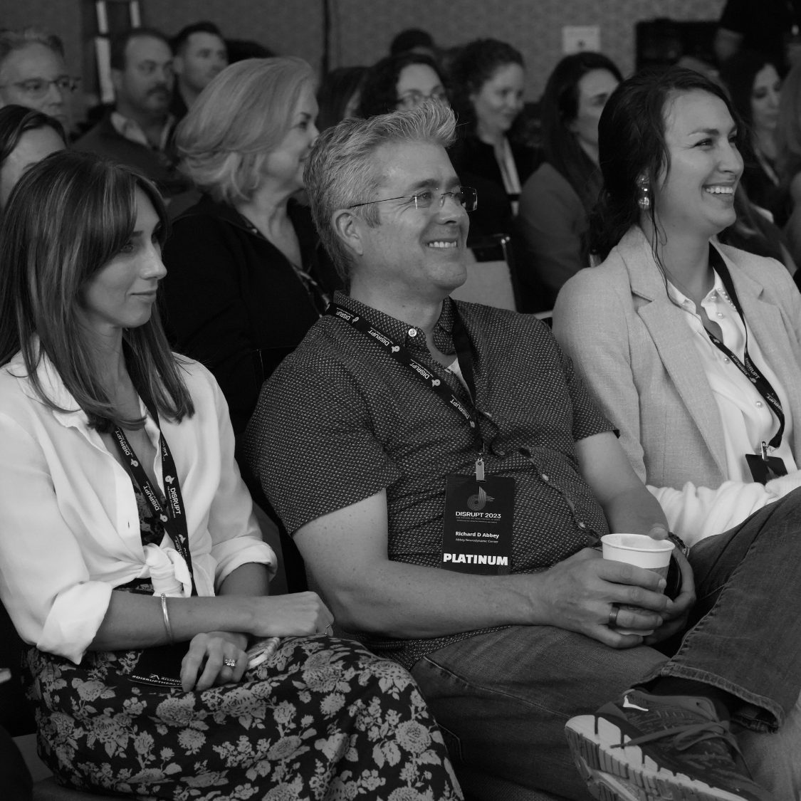 A smiling audience at Disrupt, in black and white