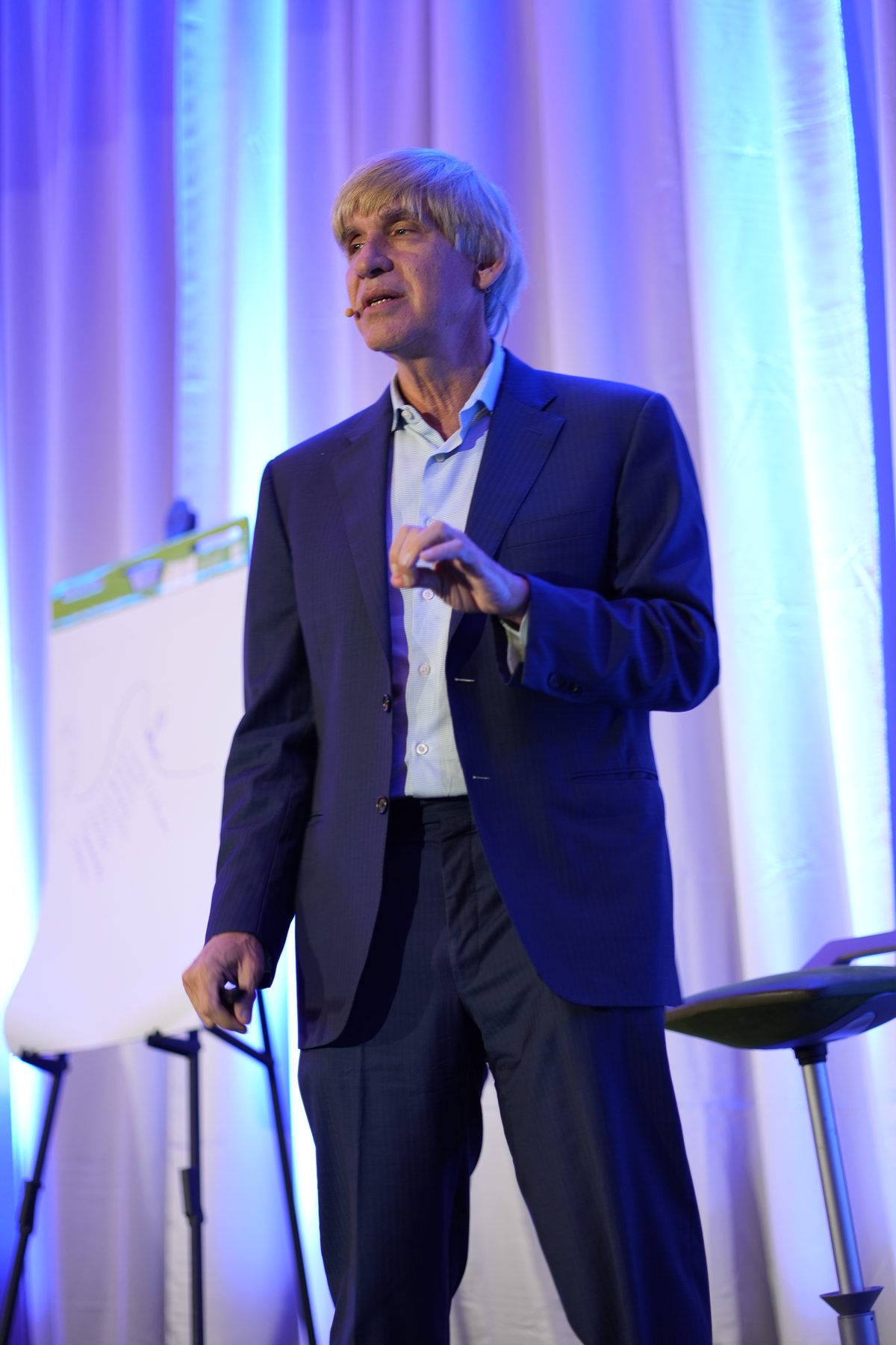 A speaker presenting on the Health Experts Alliance stage