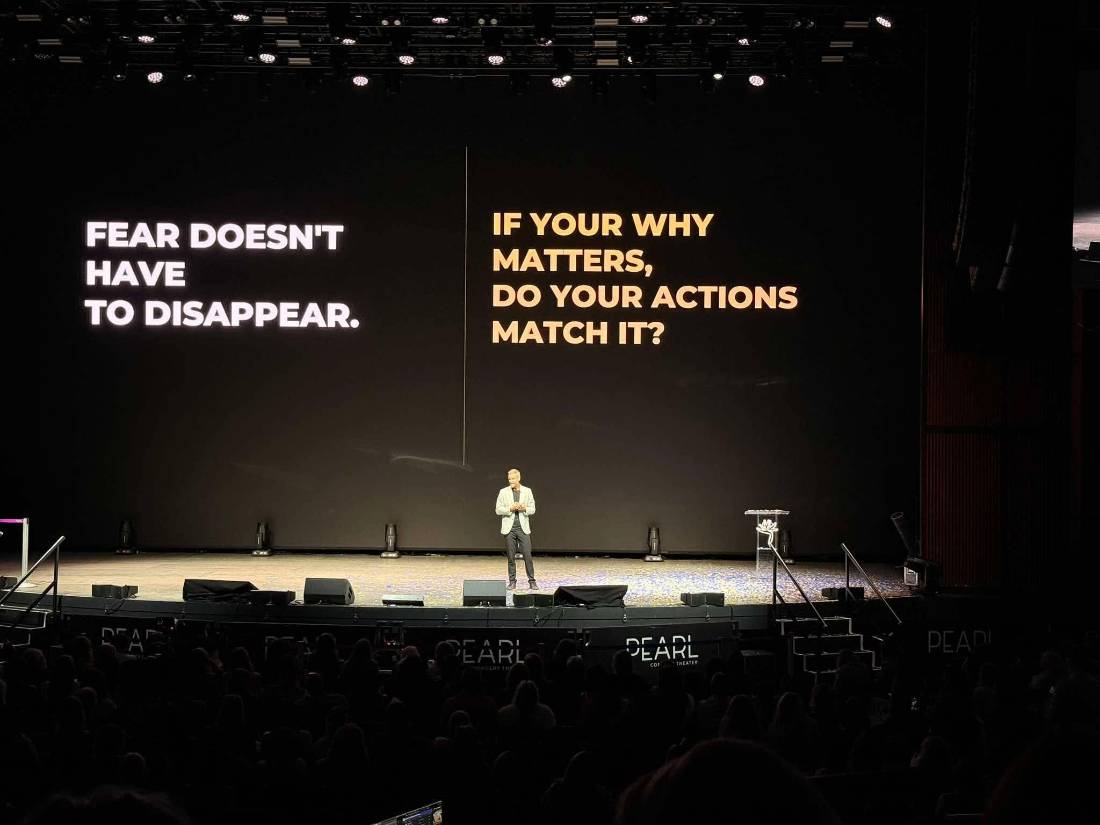 Rob Sperry speaking on a large theater stage in front of a full audience