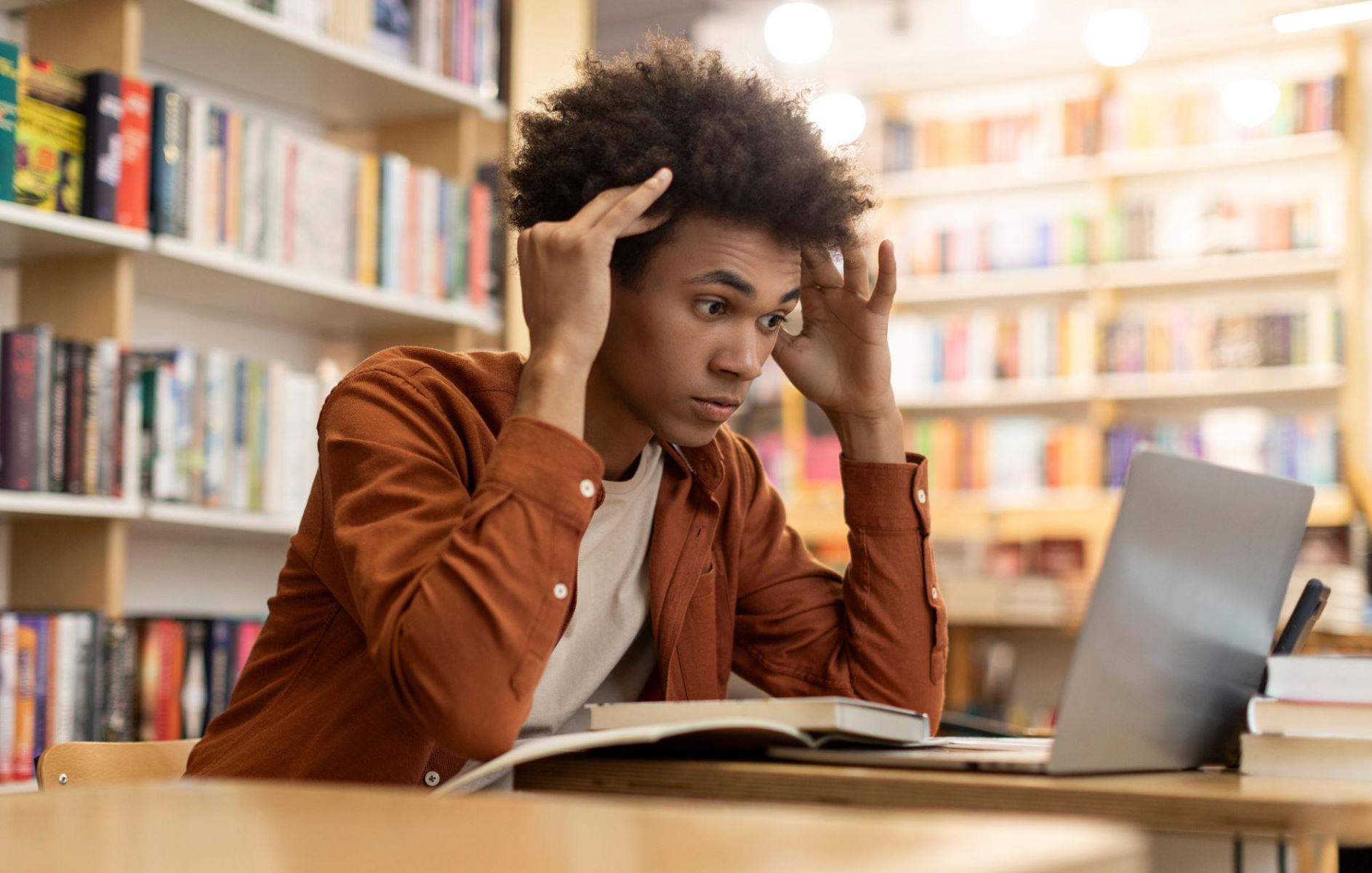 A student looking at a laptop with multiple tabs/pages open, looking confused rather than devastated.