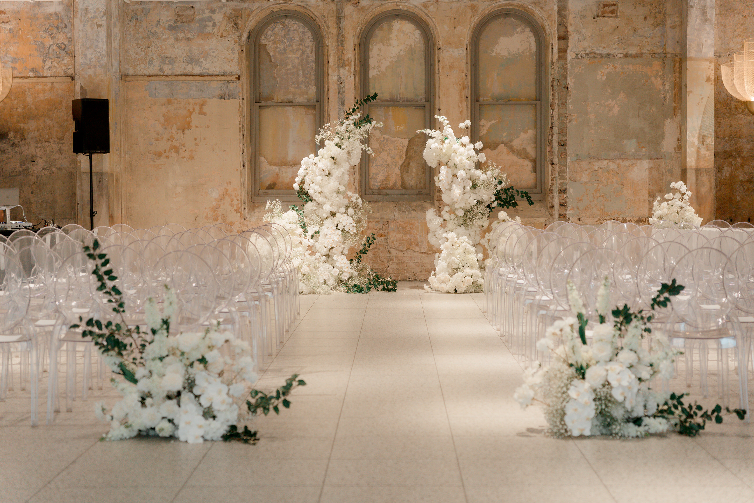 White wedding ceremony florals framing a sandstone arched room in Sydney