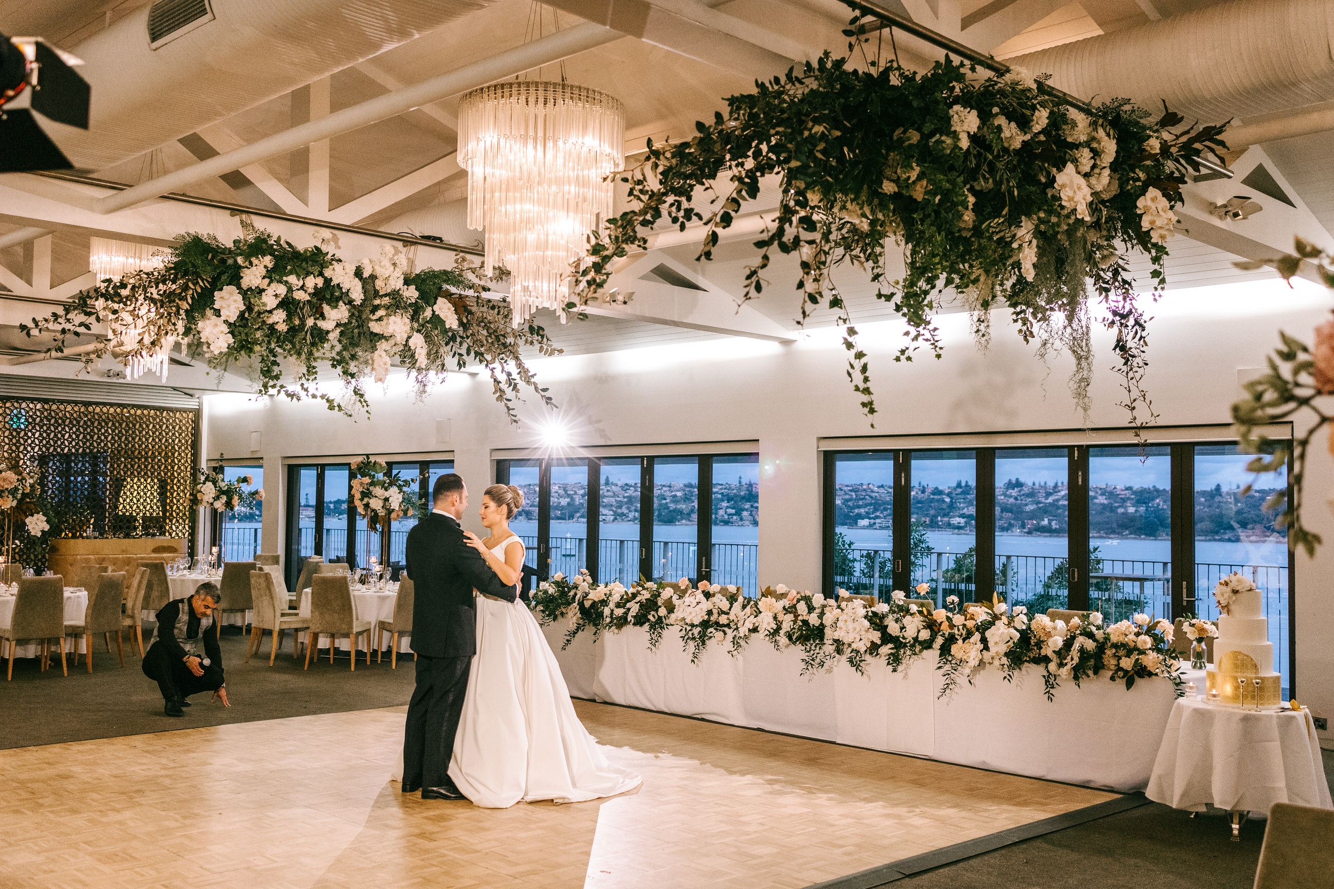 Couple dancing under a hanging greenery installation in a waterfront room