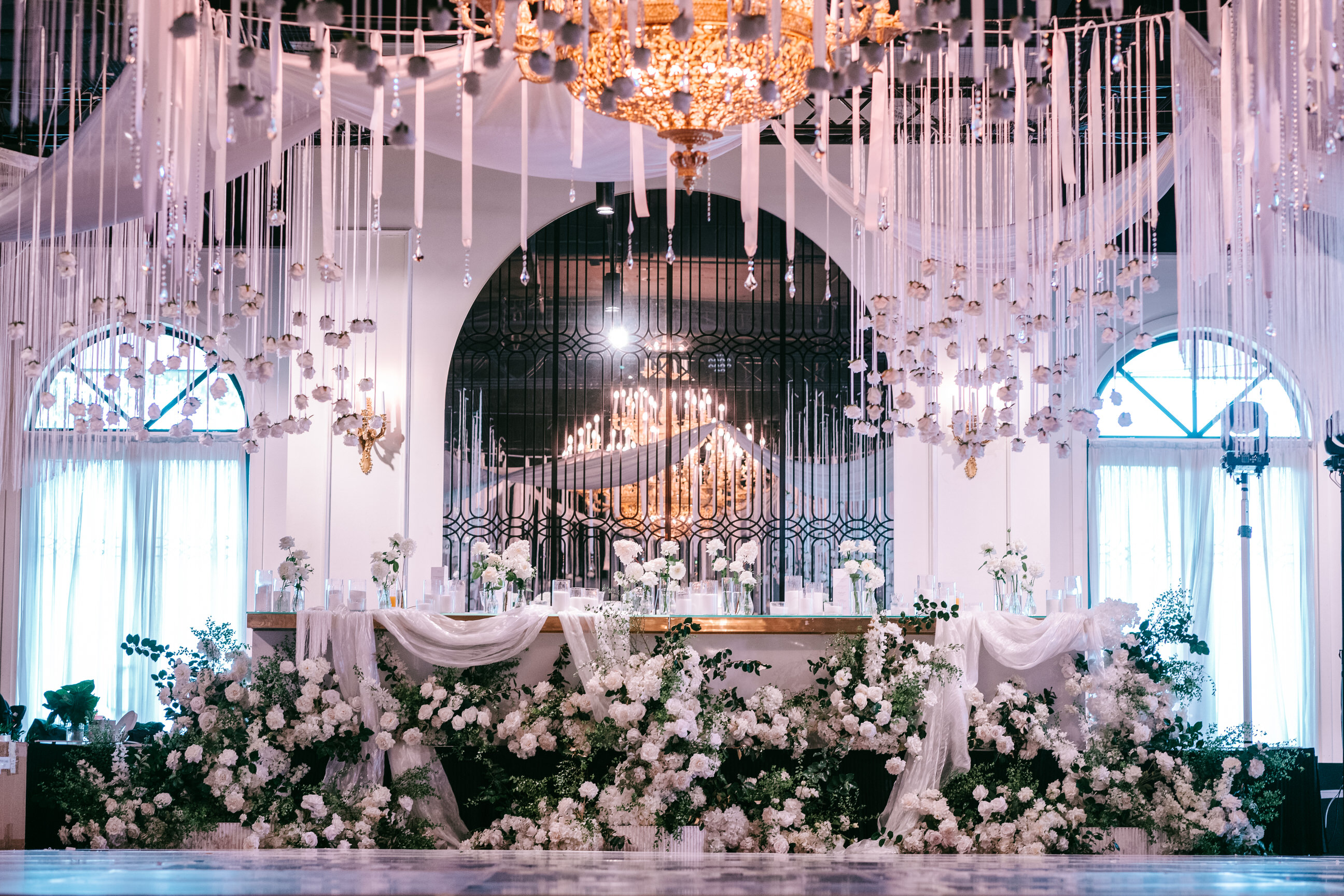Hanging floral ceiling installation with chandelier in a blush ballroom