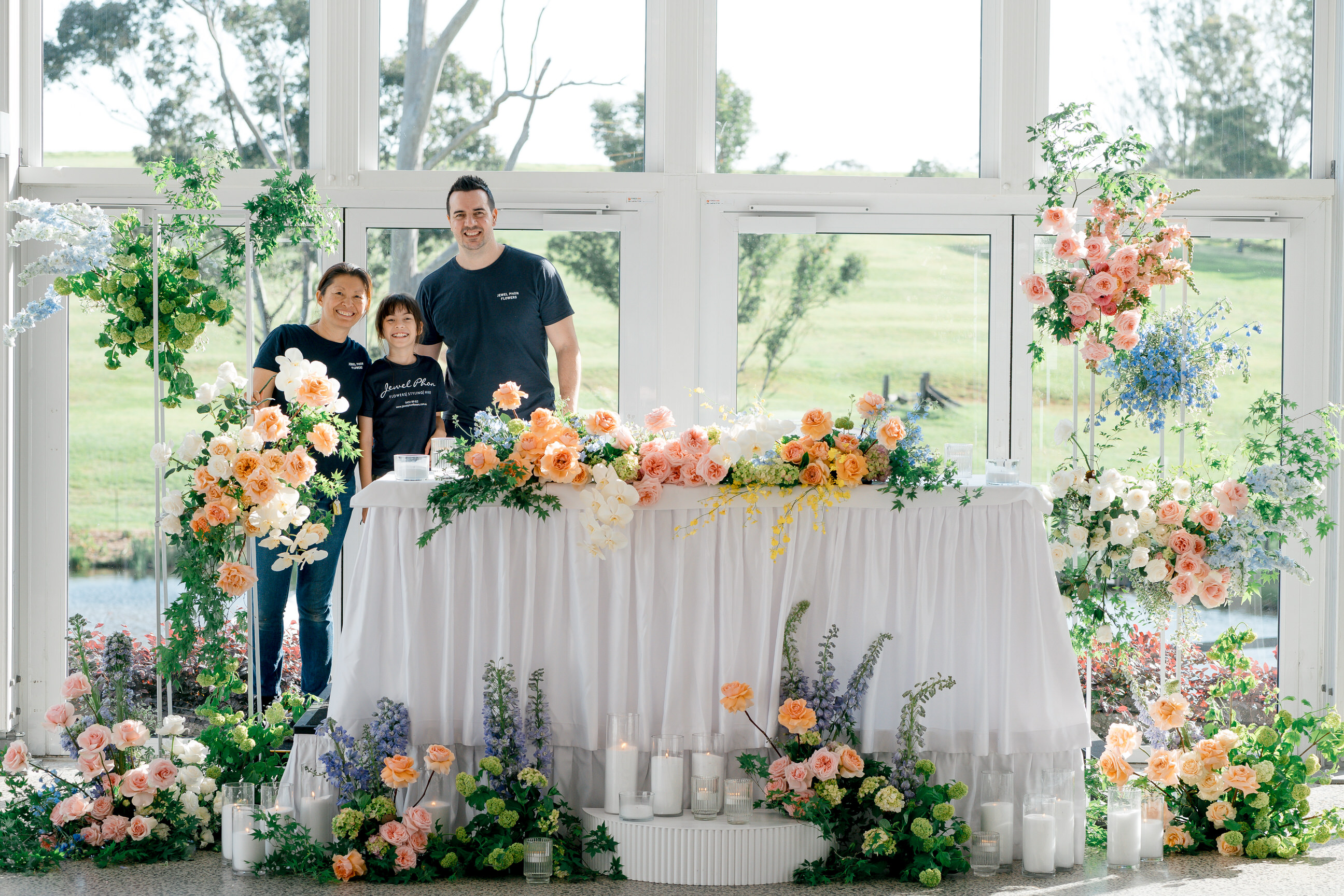 Jewel and Damien Phon behind a pastel bridal table in a glasshouse venue