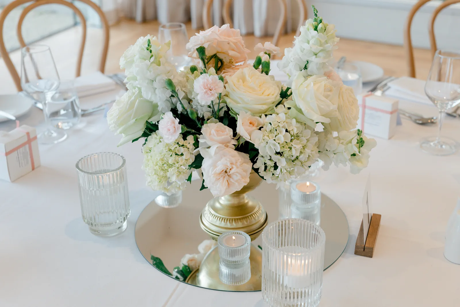 White and blush centrepiece on a mirror with candles