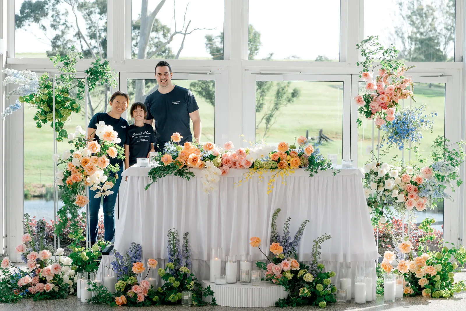 Jewel and Damien Phon behind a pastel bridal table in a glasshouse venue