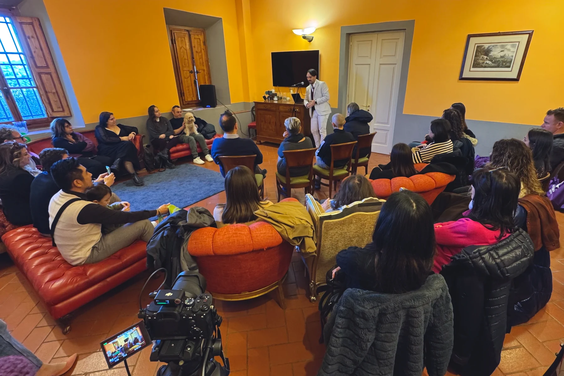 Lorenzo parla al microfono davanti ai partecipanti riuniti in sala
