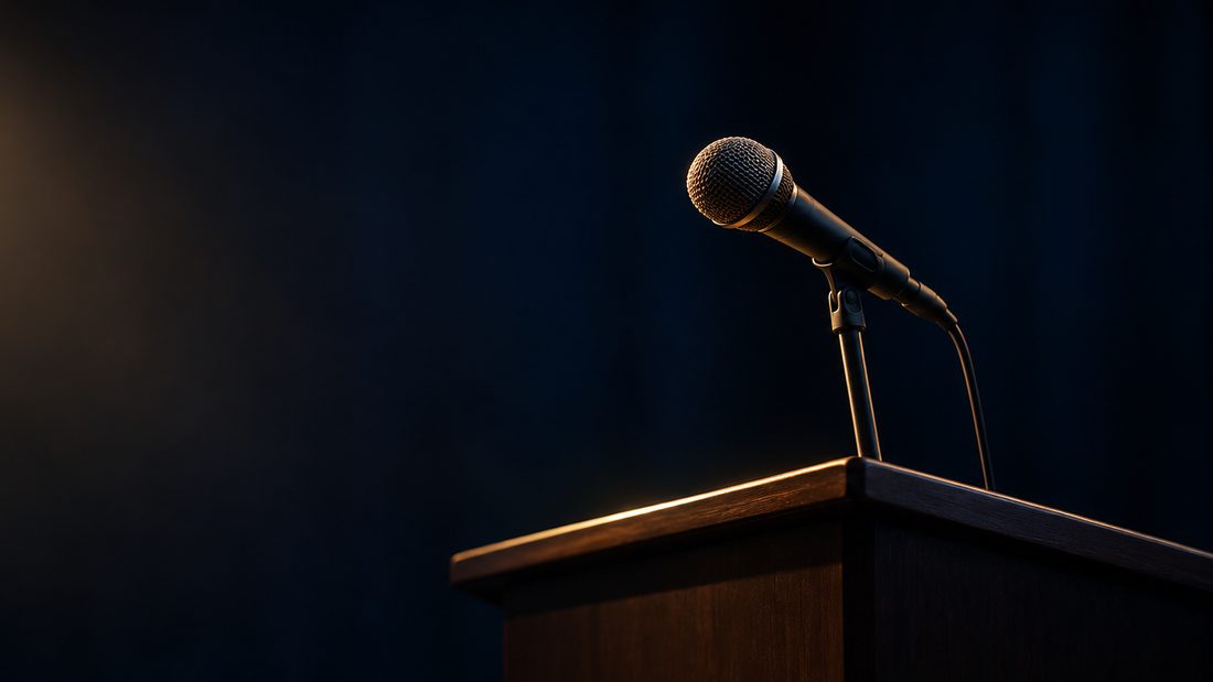 A microphone at an empty podium under a single warm light