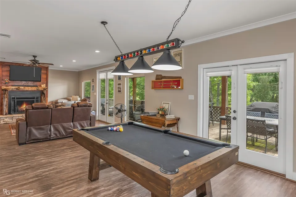 Open game room with a pool table and doors to the deck