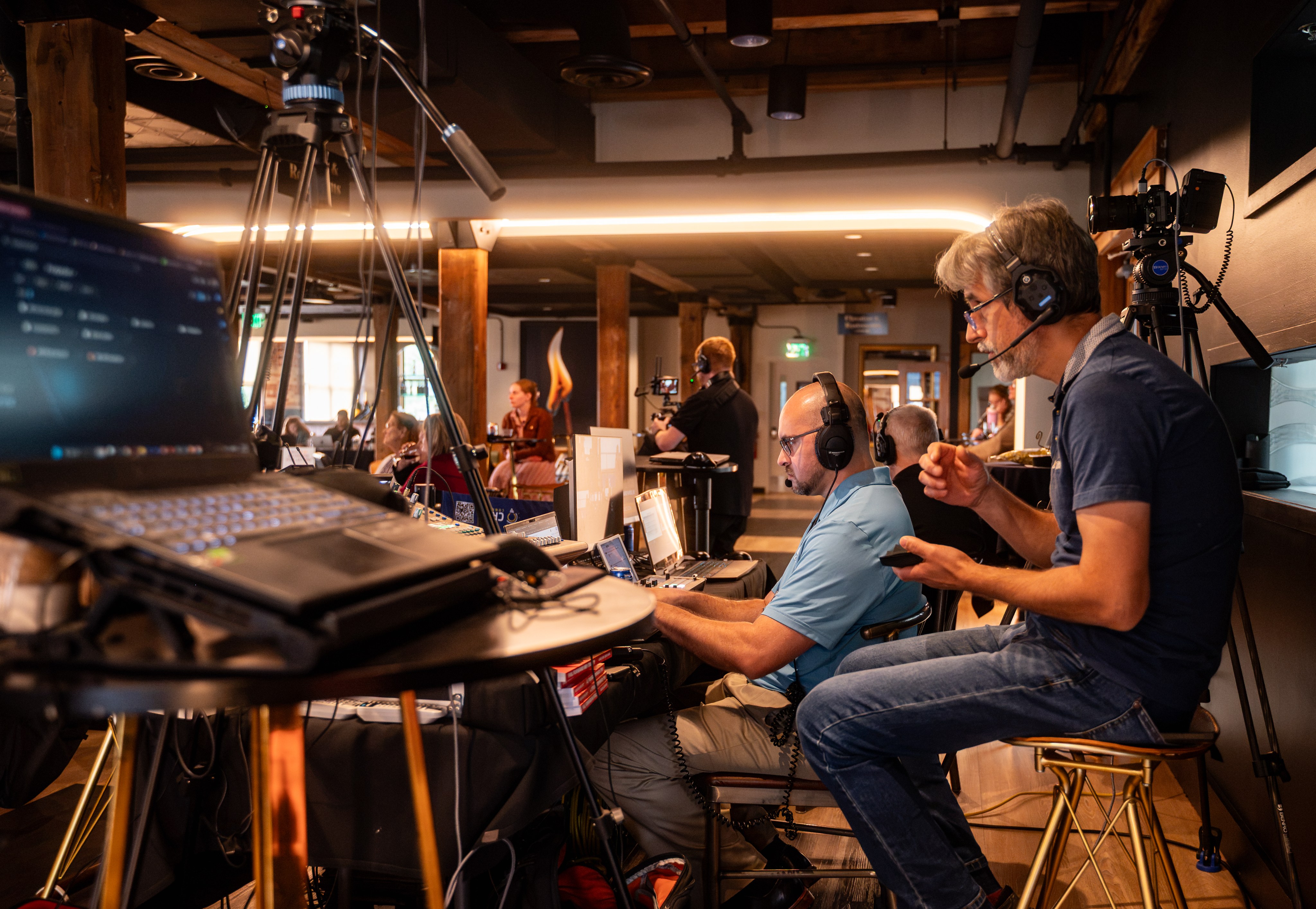 A production crew on headsets at a row of monitors and laptops during an event