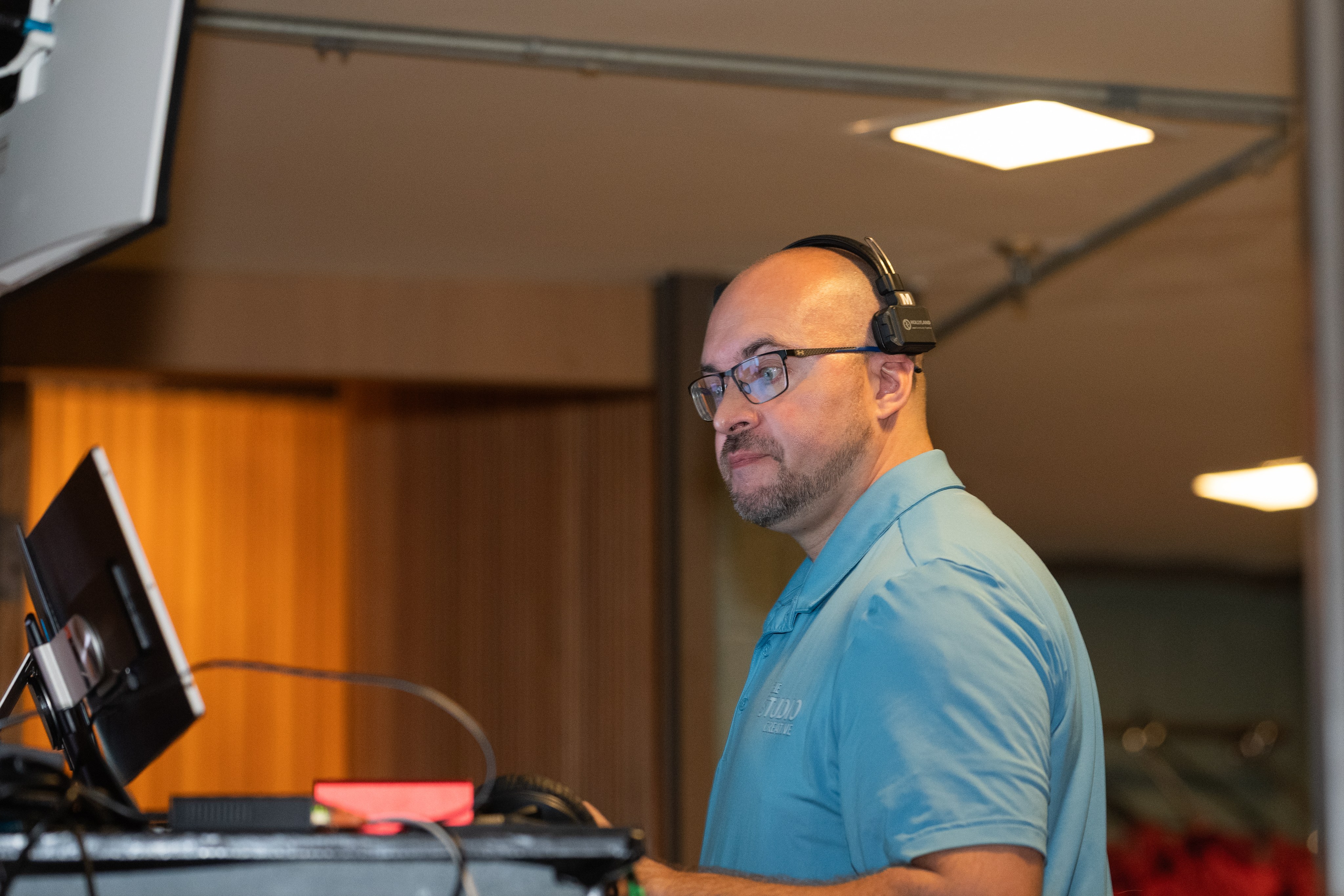 An operator on headset at the program laptop during a live conference broadcast