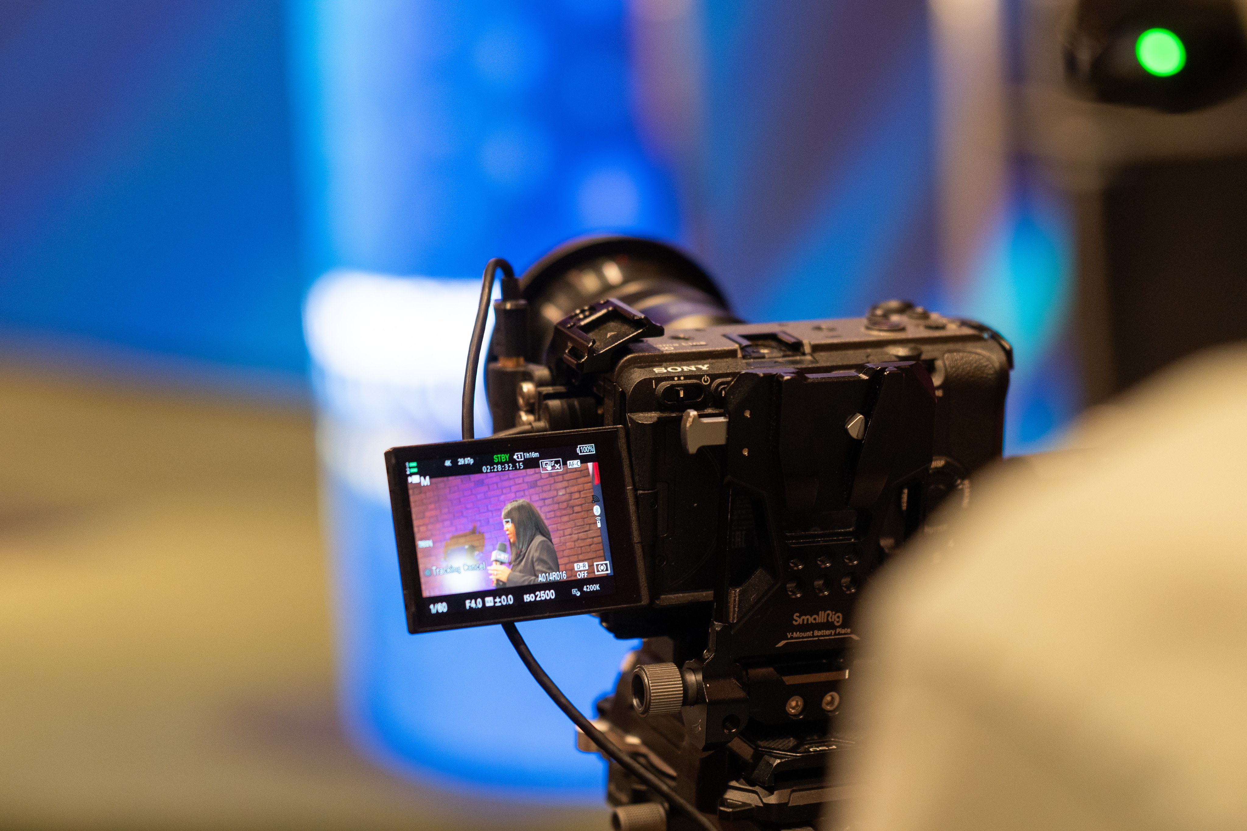 A cinema camera and its monitor rigged for a live event, lit blue