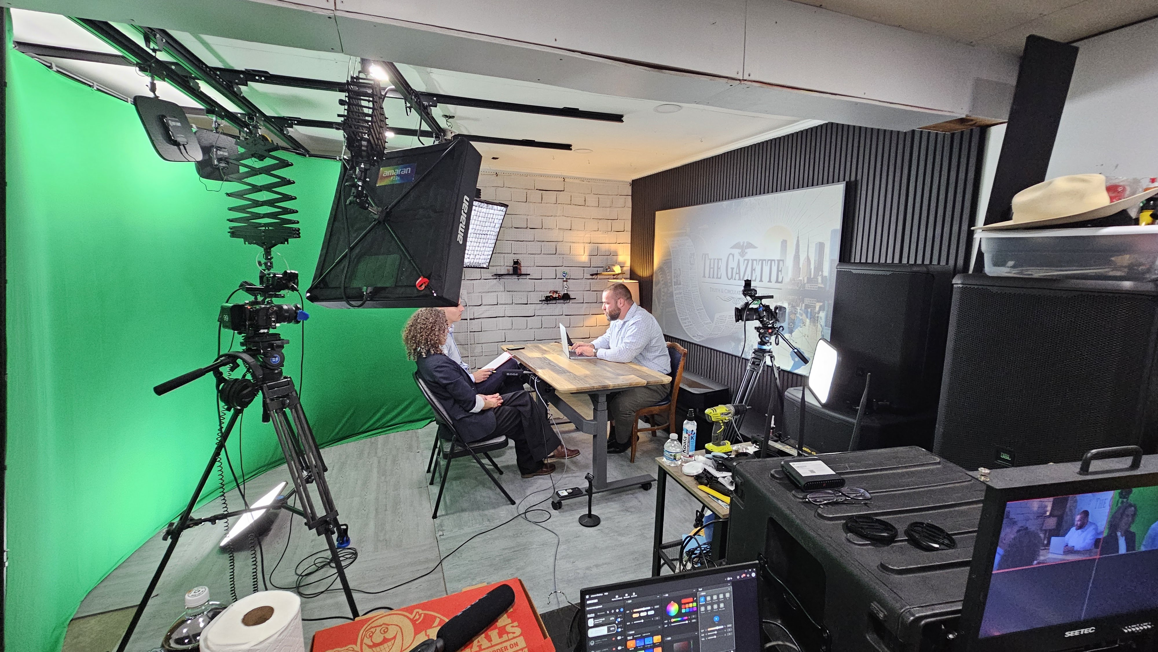 Behind the scenes on The Gazette: green screen on the left, the practical newspaper office set with its masthead wall on the right