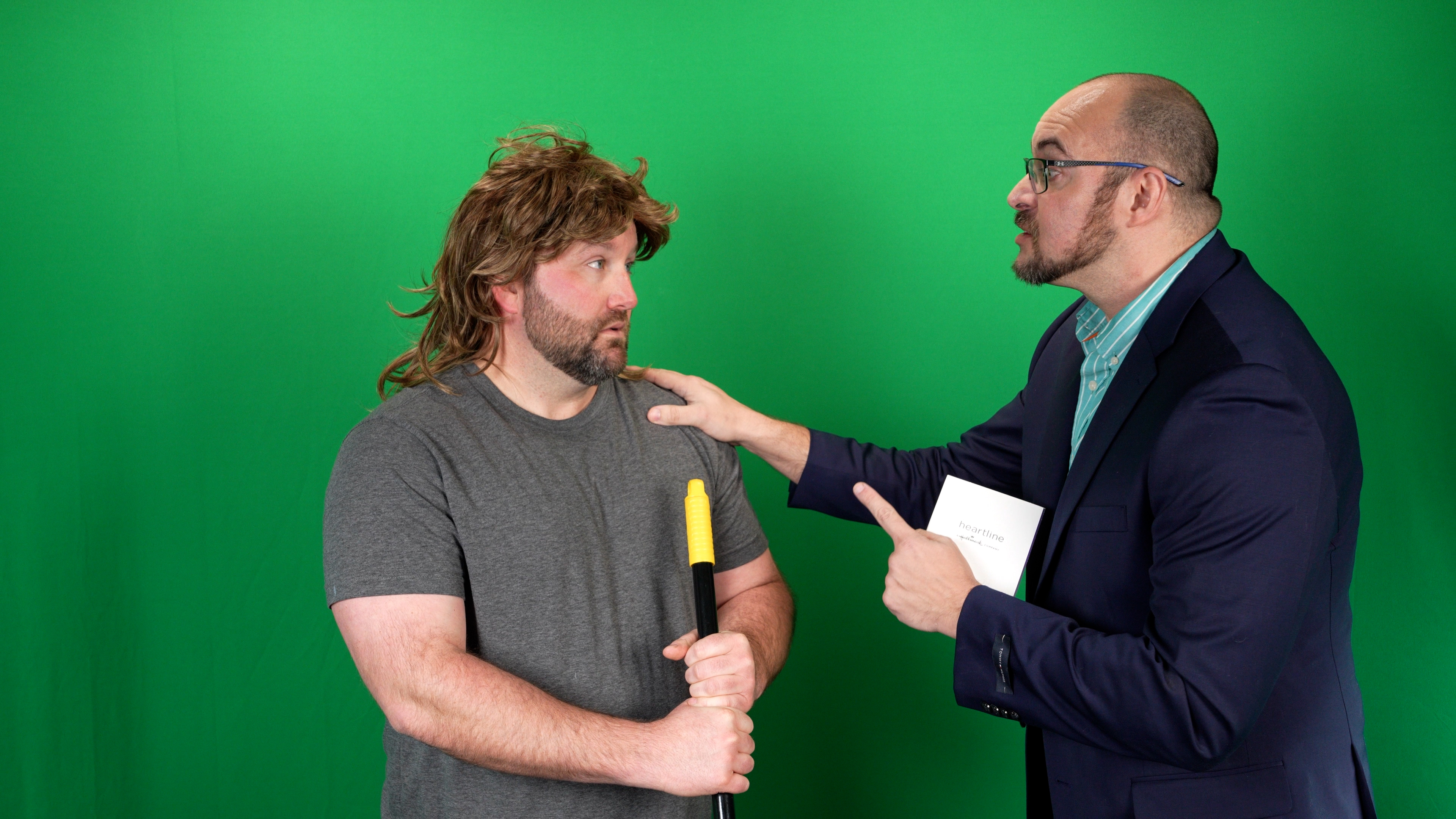 The same frame on set: the two performers in front of the green screen