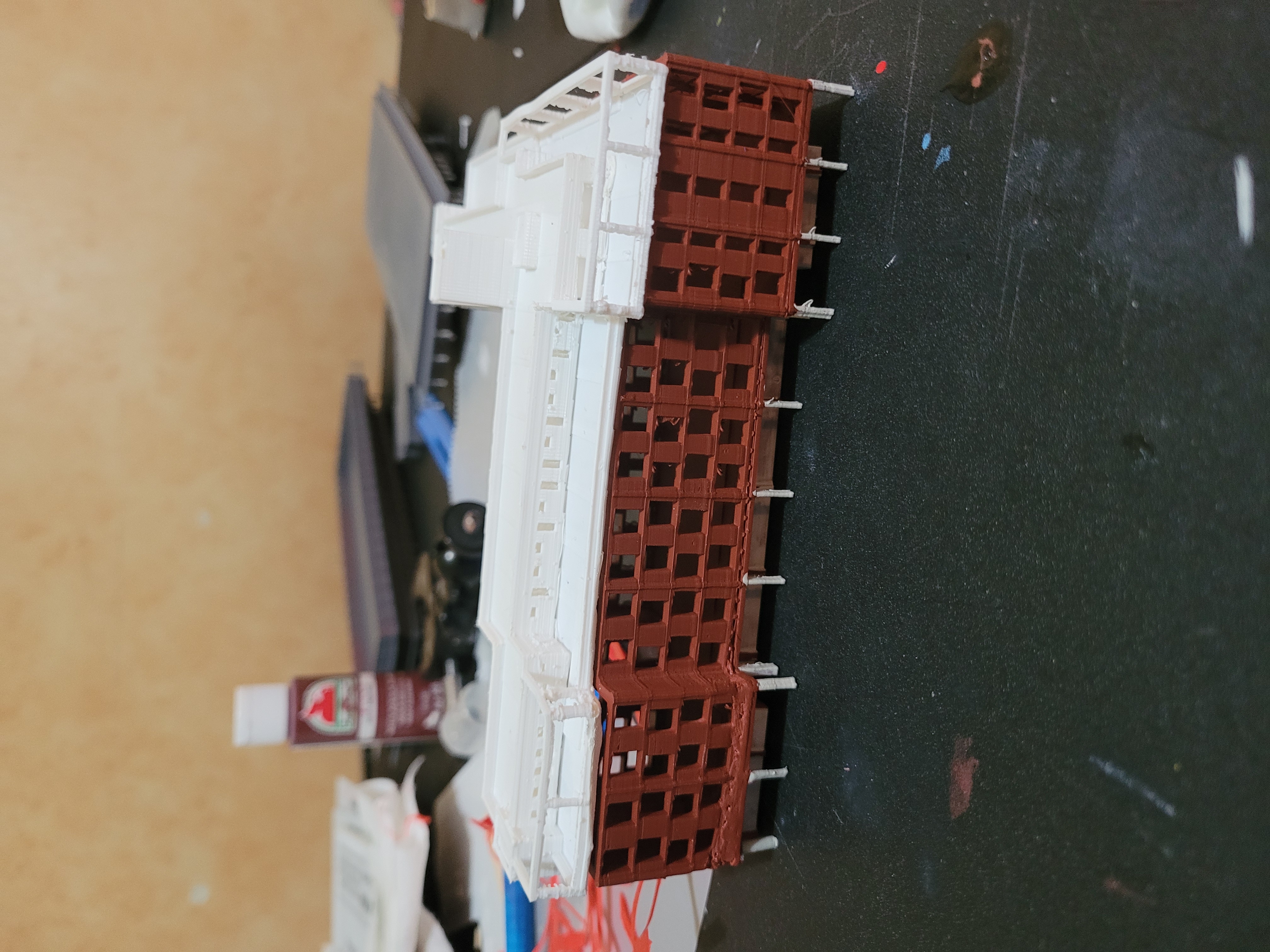 A partly finished model building with a painted red brick base and an unpainted white upper structure