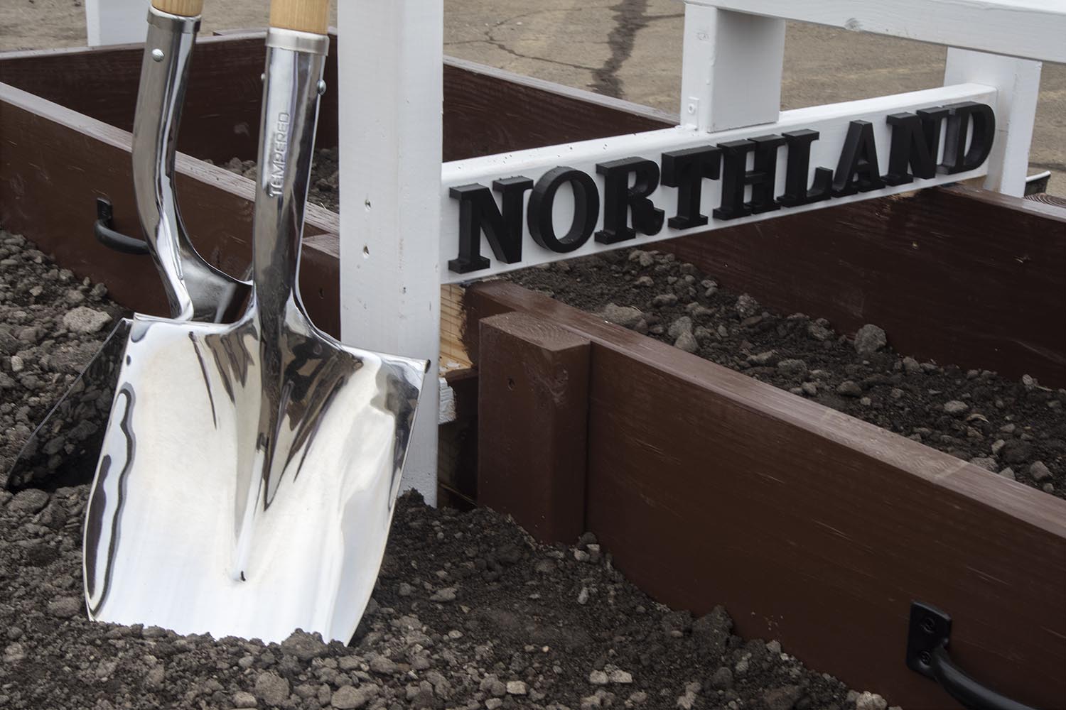 Chrome ceremonial shovels leaning against a custom Northland sign filled with gravel