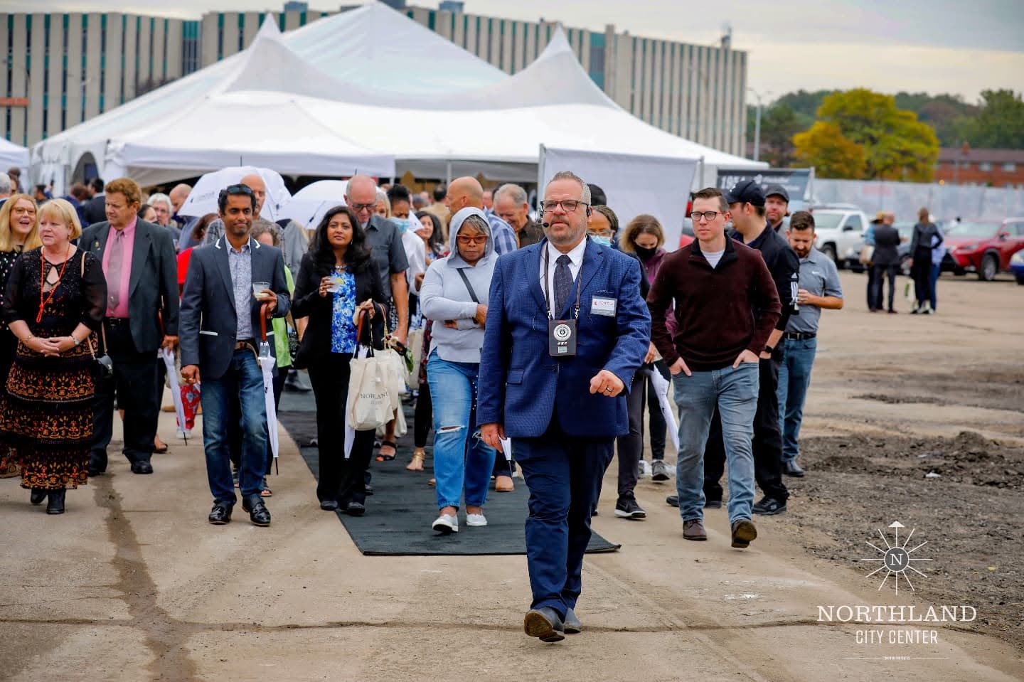 Architect Bruce Kopytek in a suit walking through guests at the Northland City Center groundbreaking