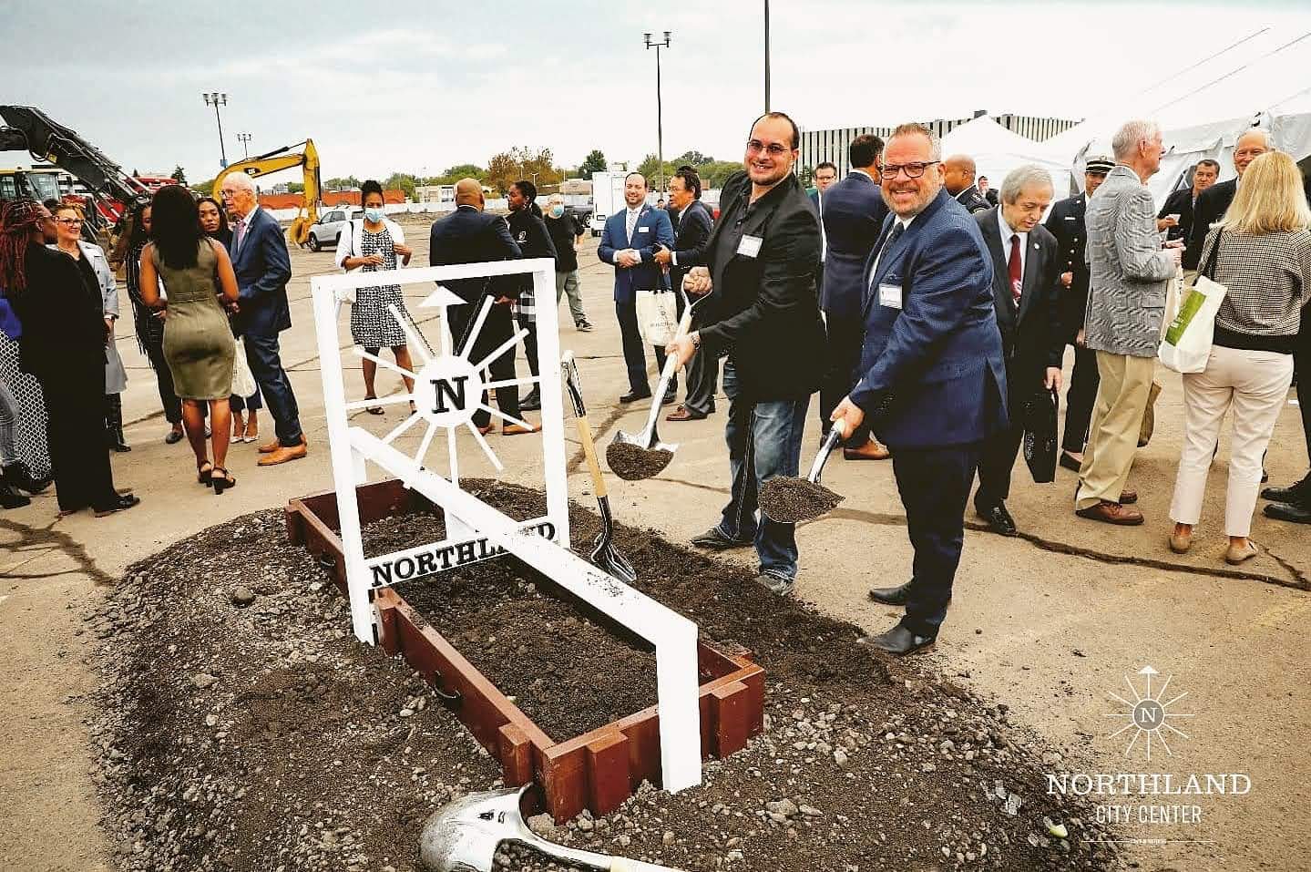 Guests with ceremonial shovels digging at a custom built Northland entryway sign at the groundbreaking