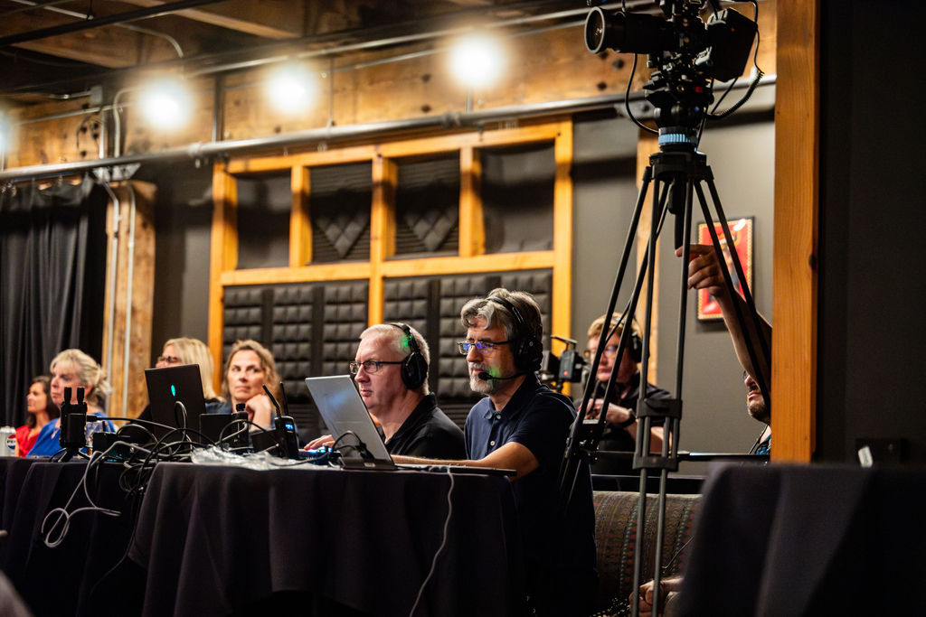 The Studio Creative crew working a row of monitors and a camera at the back of a conference room