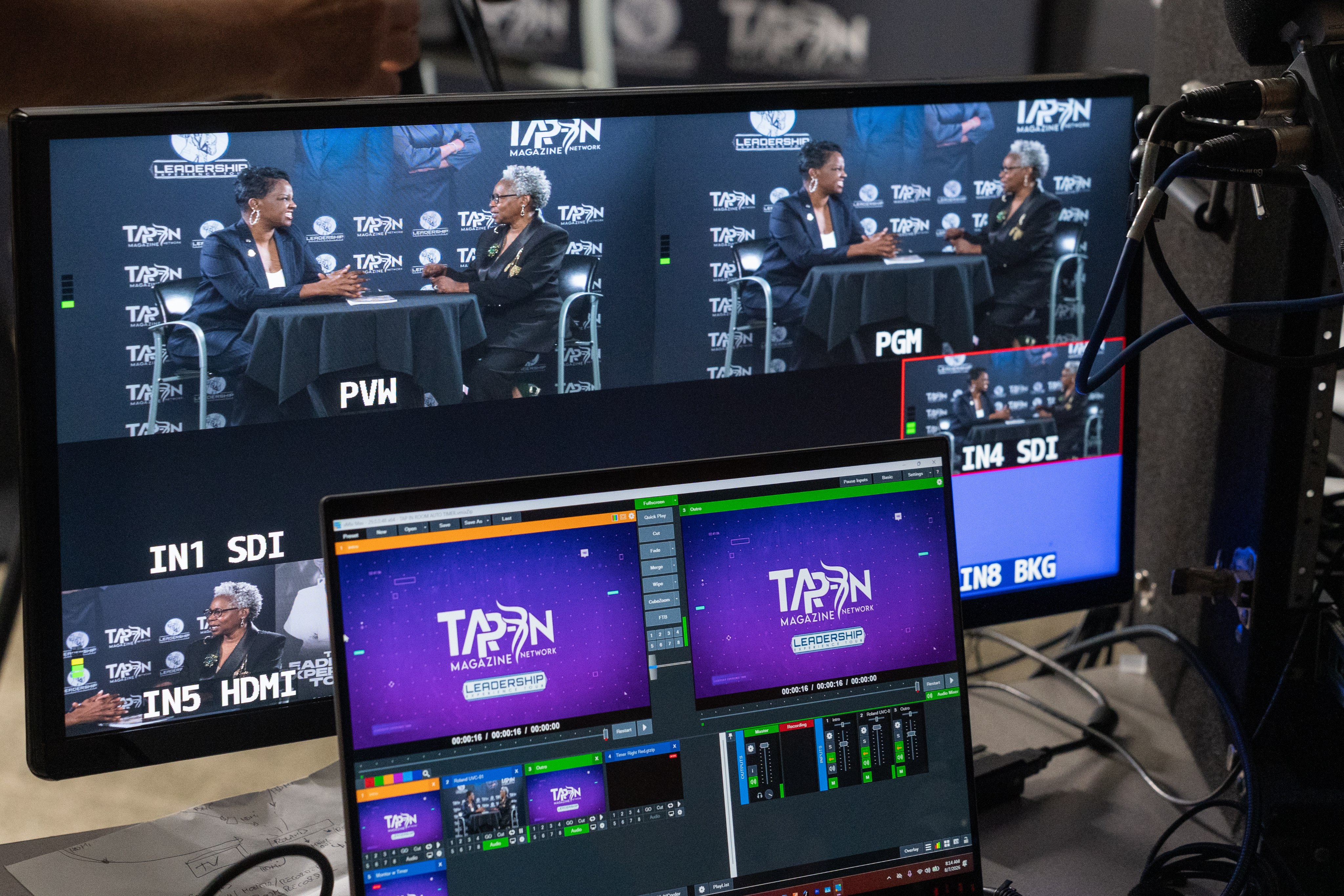 A multiview monitor and laptop showing a two-camera podcast interview being recorded