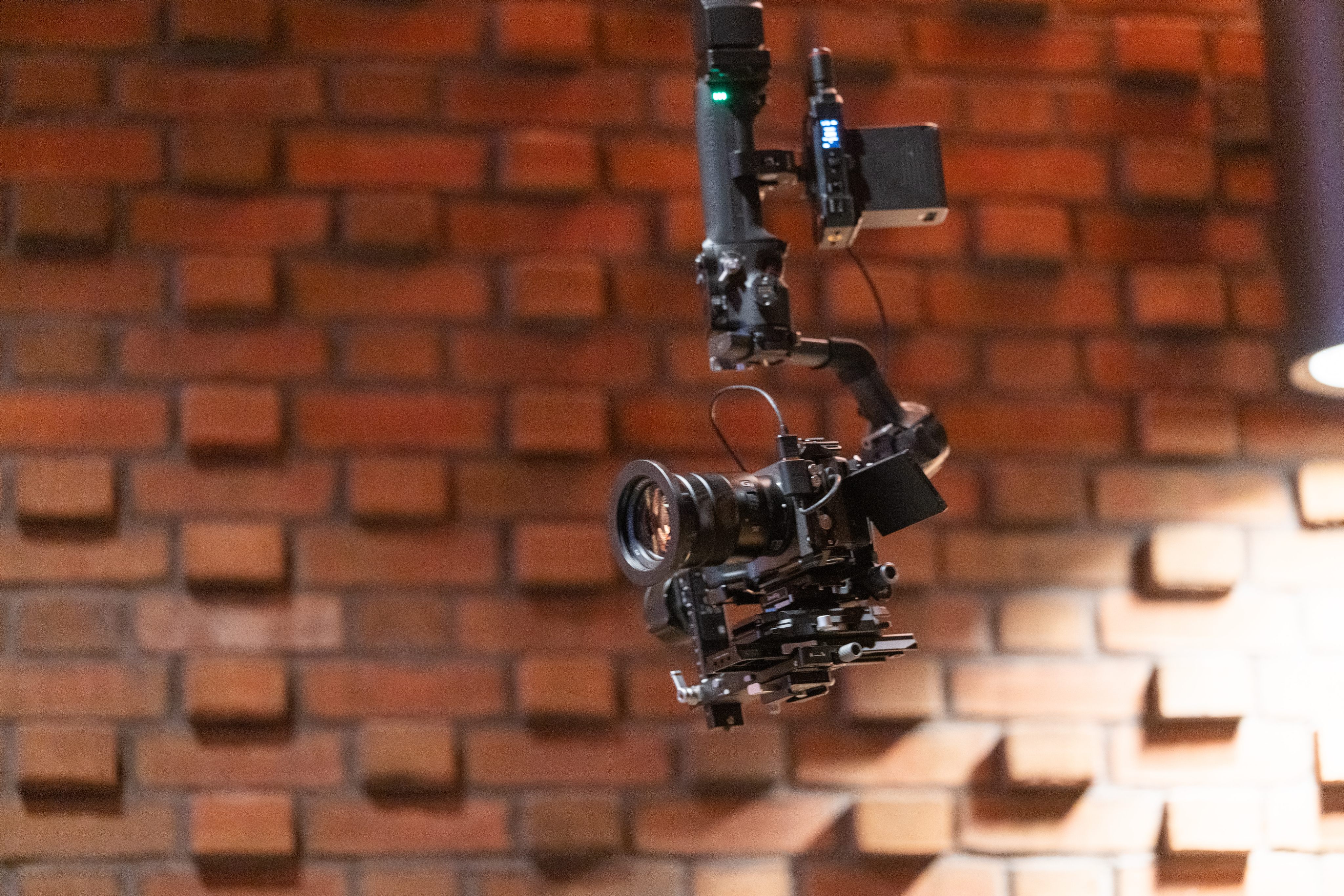 A cinema camera on a motorised gimbal rig against a brick wall