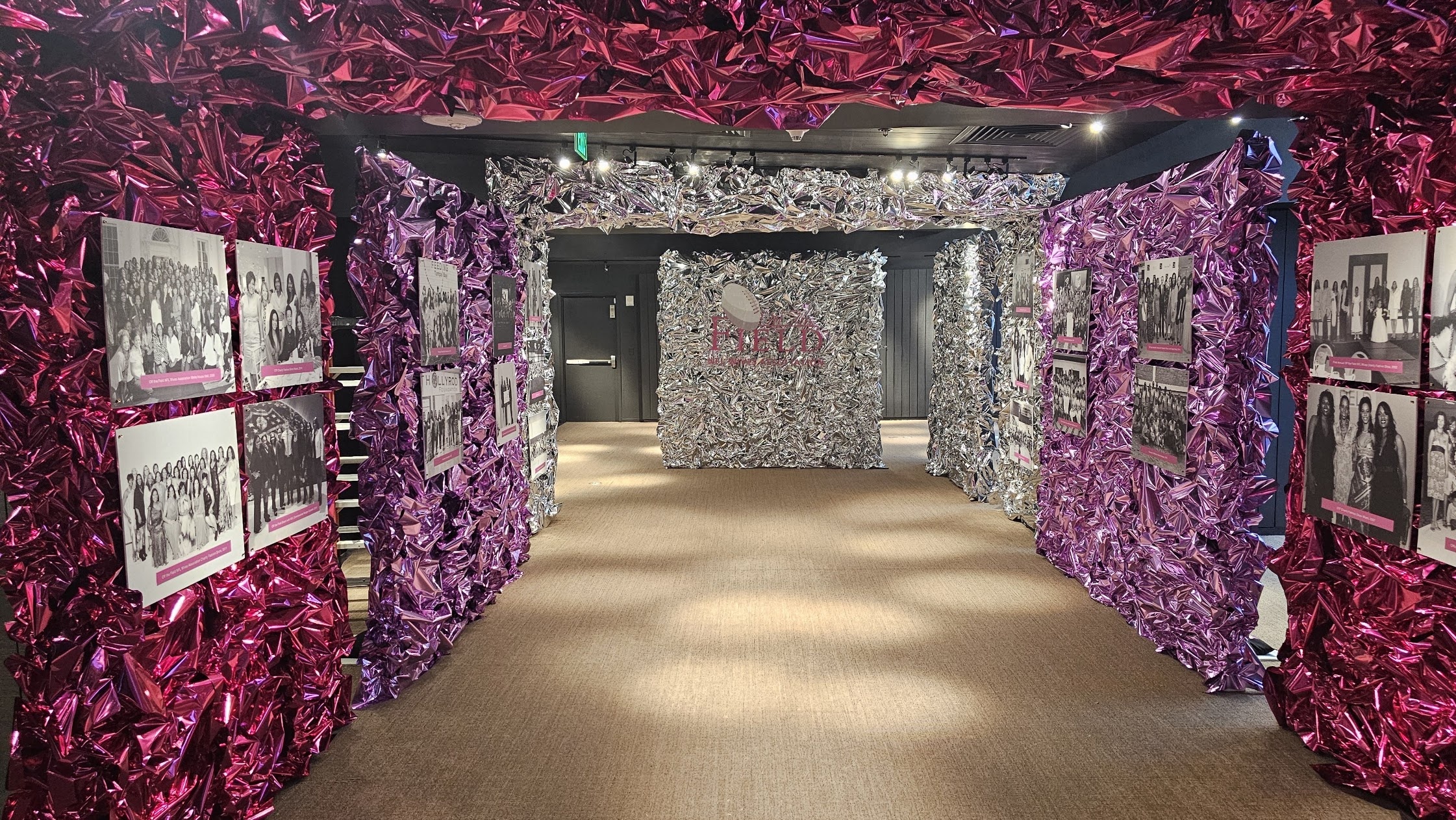 A hallway lined with pink and silver foil walls hung with black and white photographs of the association's members