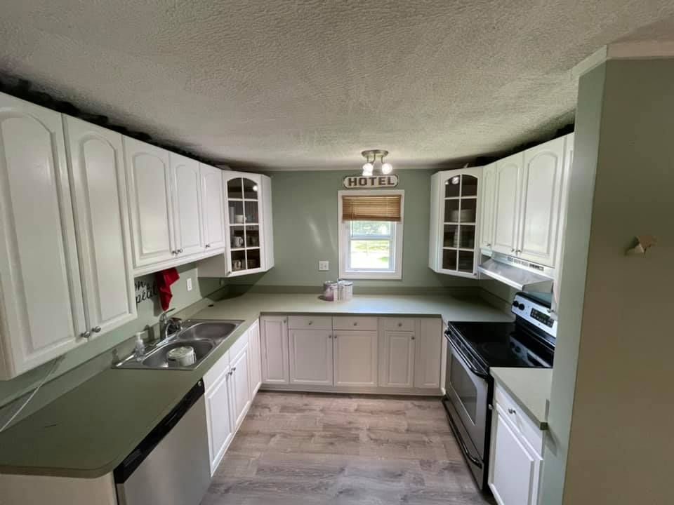Kitchen remodel with painted raised-panel cabinetry, wraparound laminate countertops, and plank-look flooring