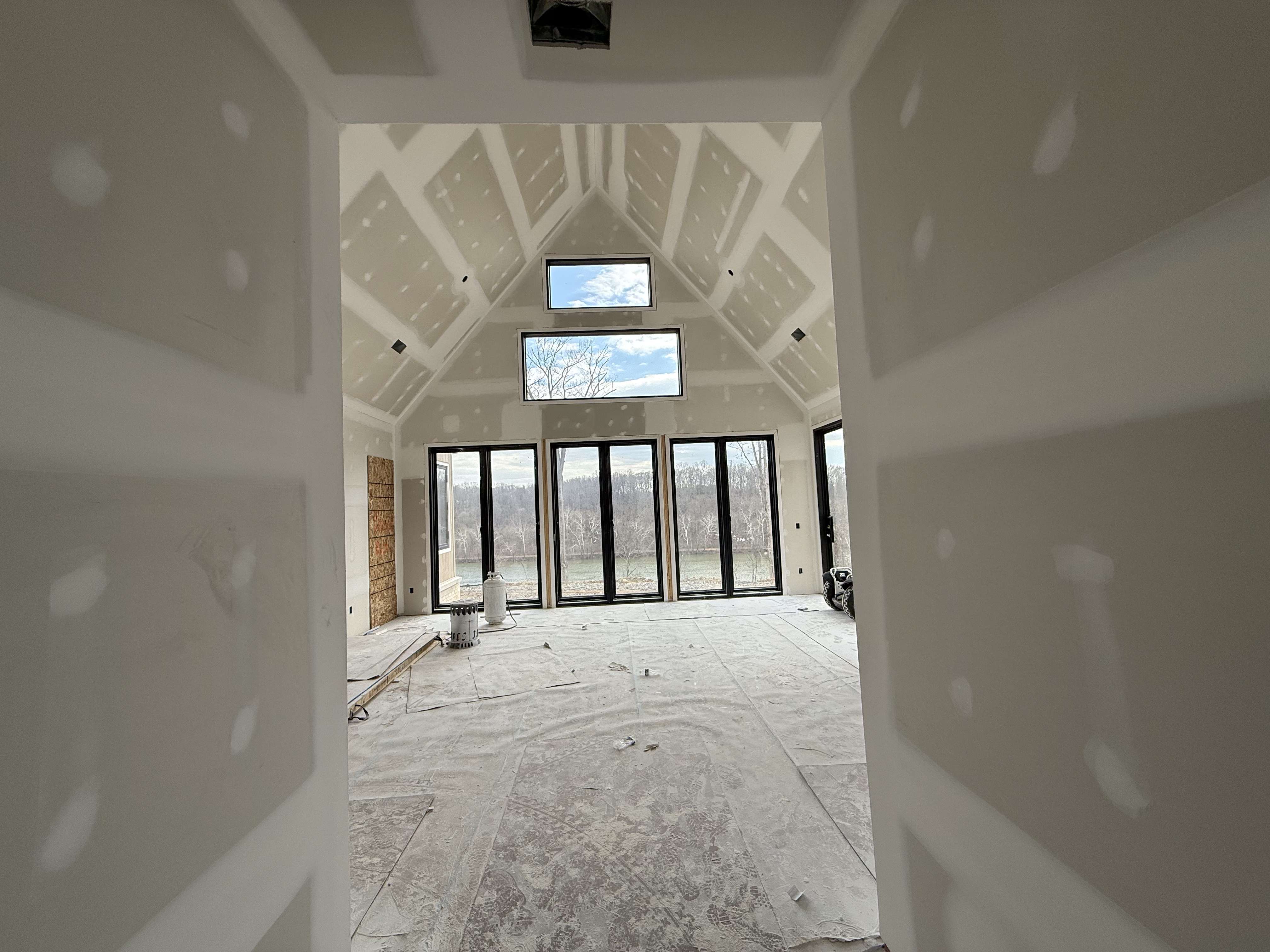 Drywall installation stage with board hung, taped joints, and first-pass compound over seams and fasteners