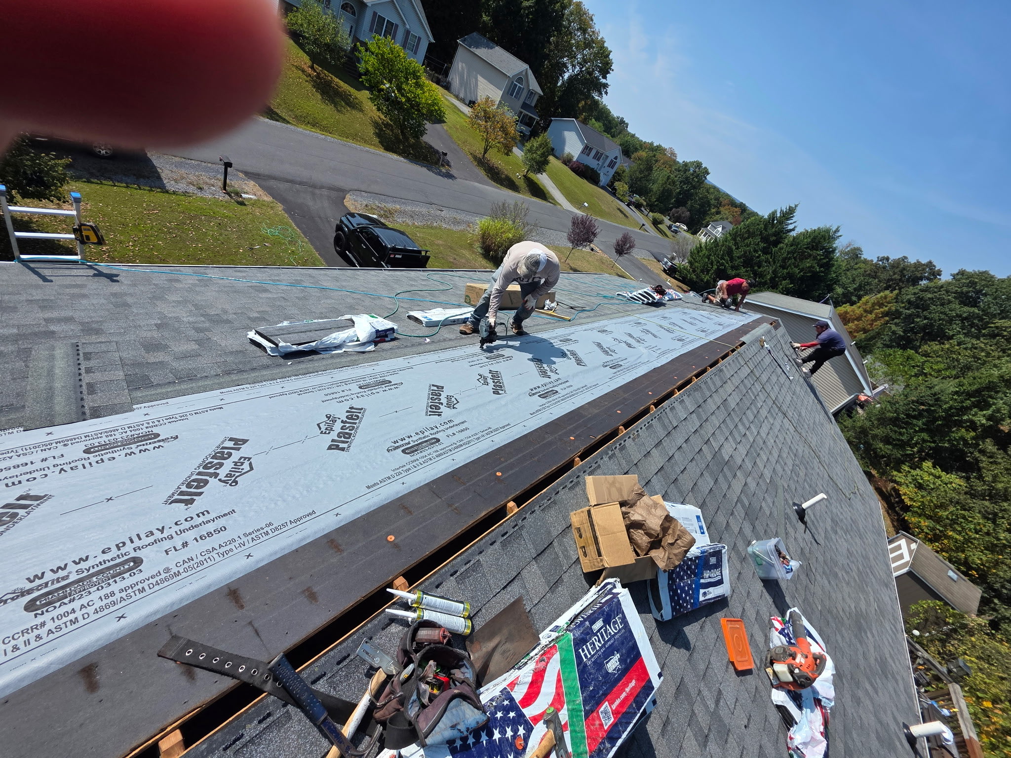 Roof replacement in progress with synthetic underlayment and new shingle courses being installed.