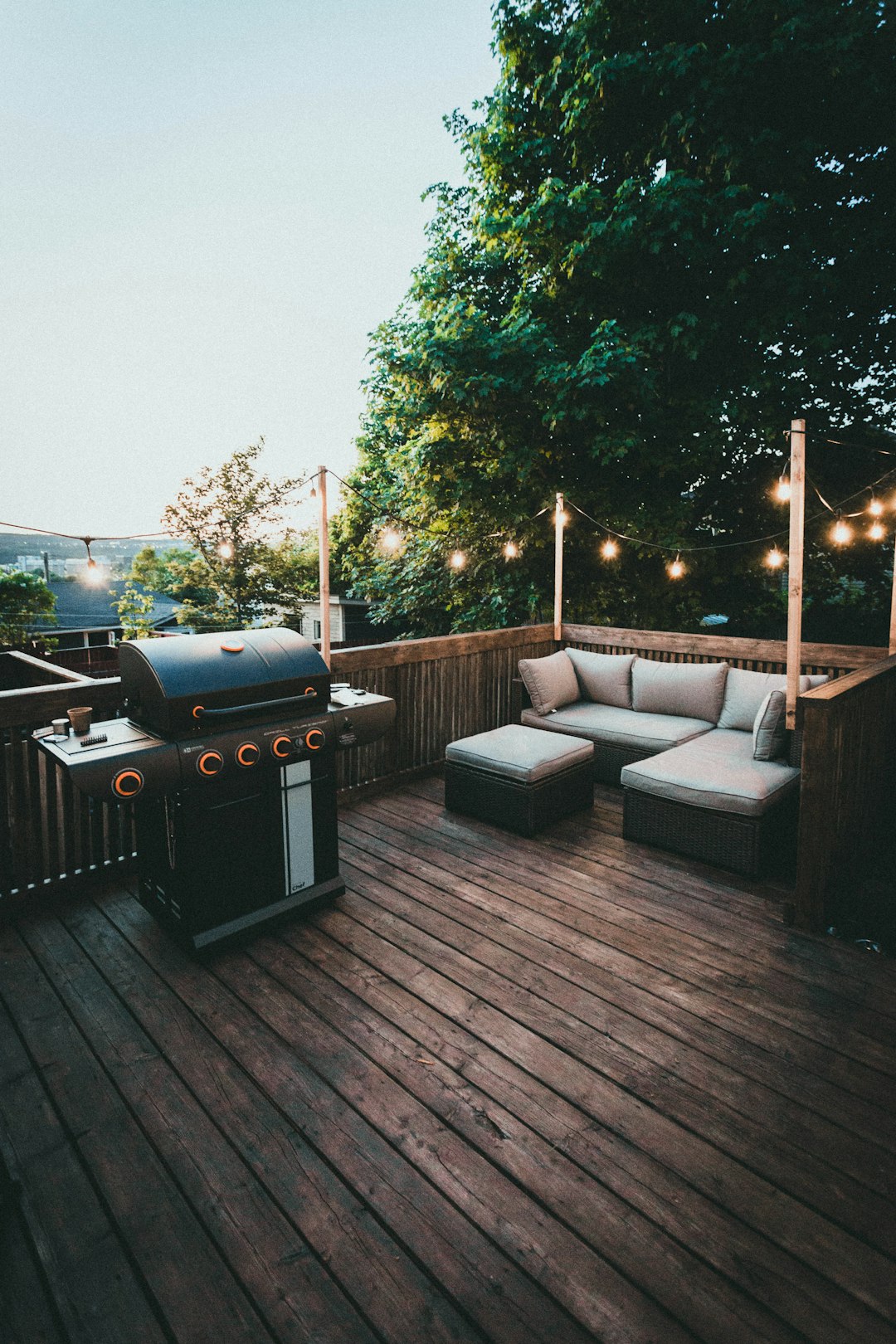 Finished deck set up as an outdoor living space with grill area, built-in seating, and string lights