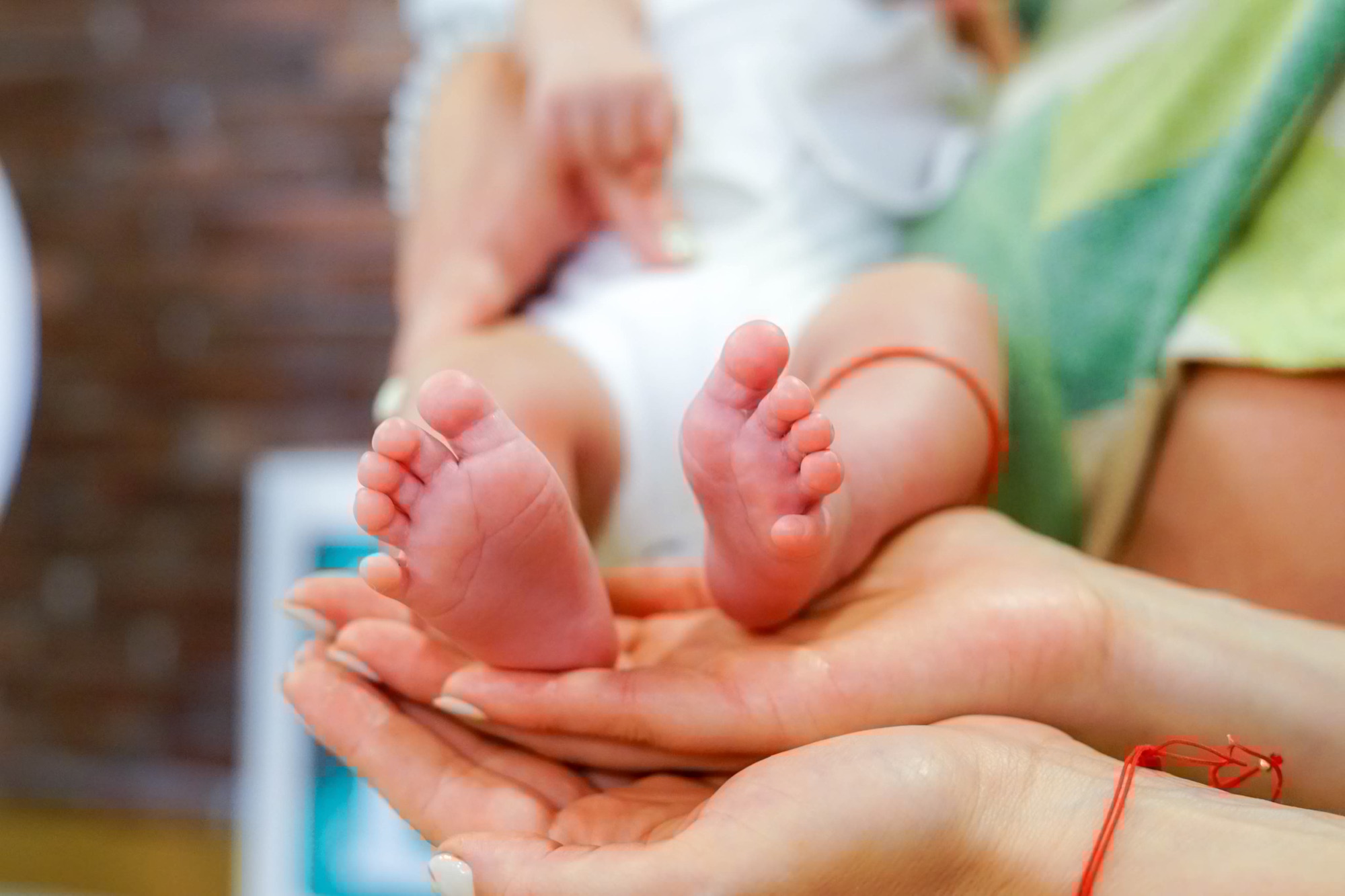 Свето кръщение – бебешки крачета в ръцете на родителите