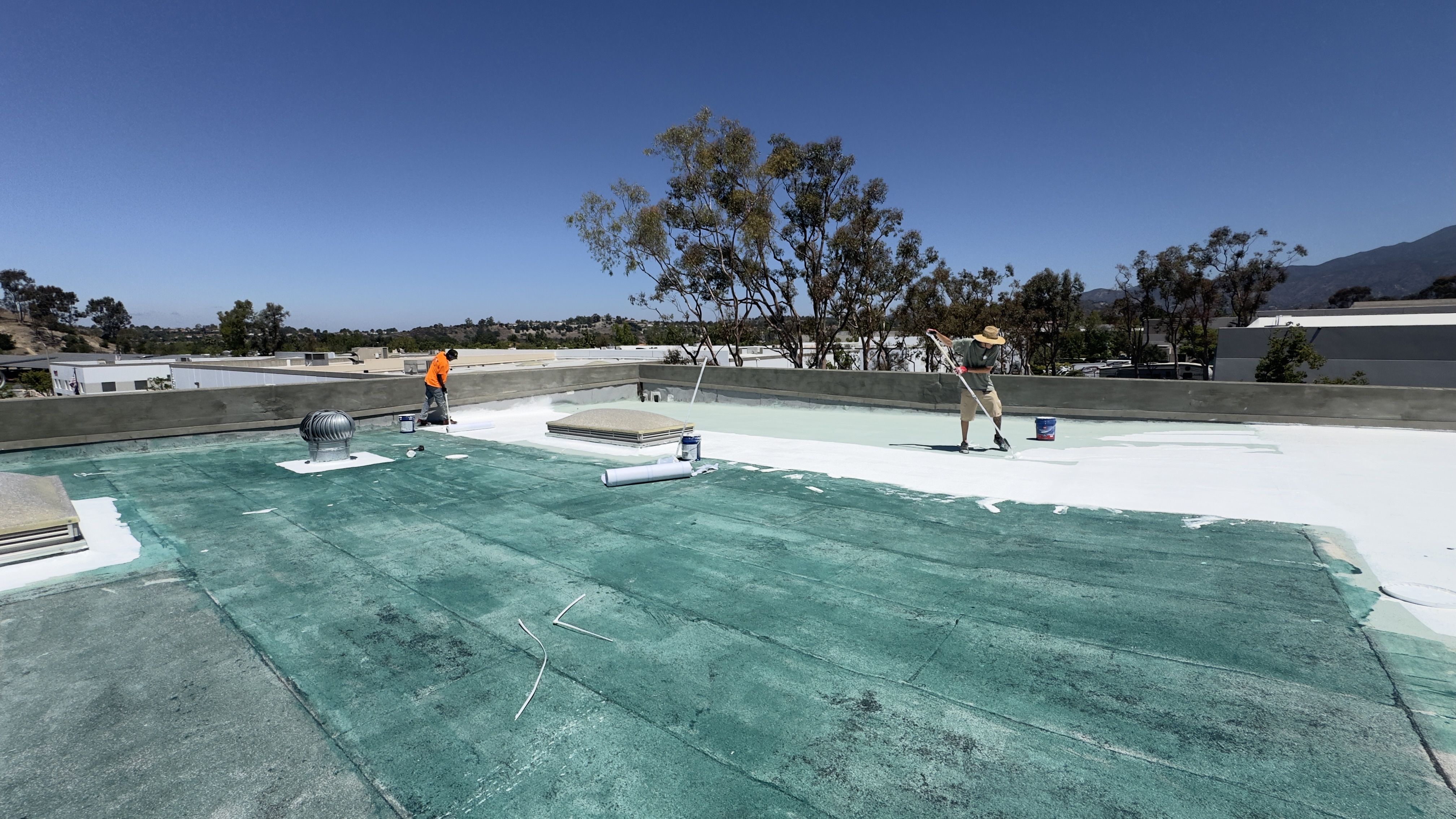 Worker applying coating on a commercial roof