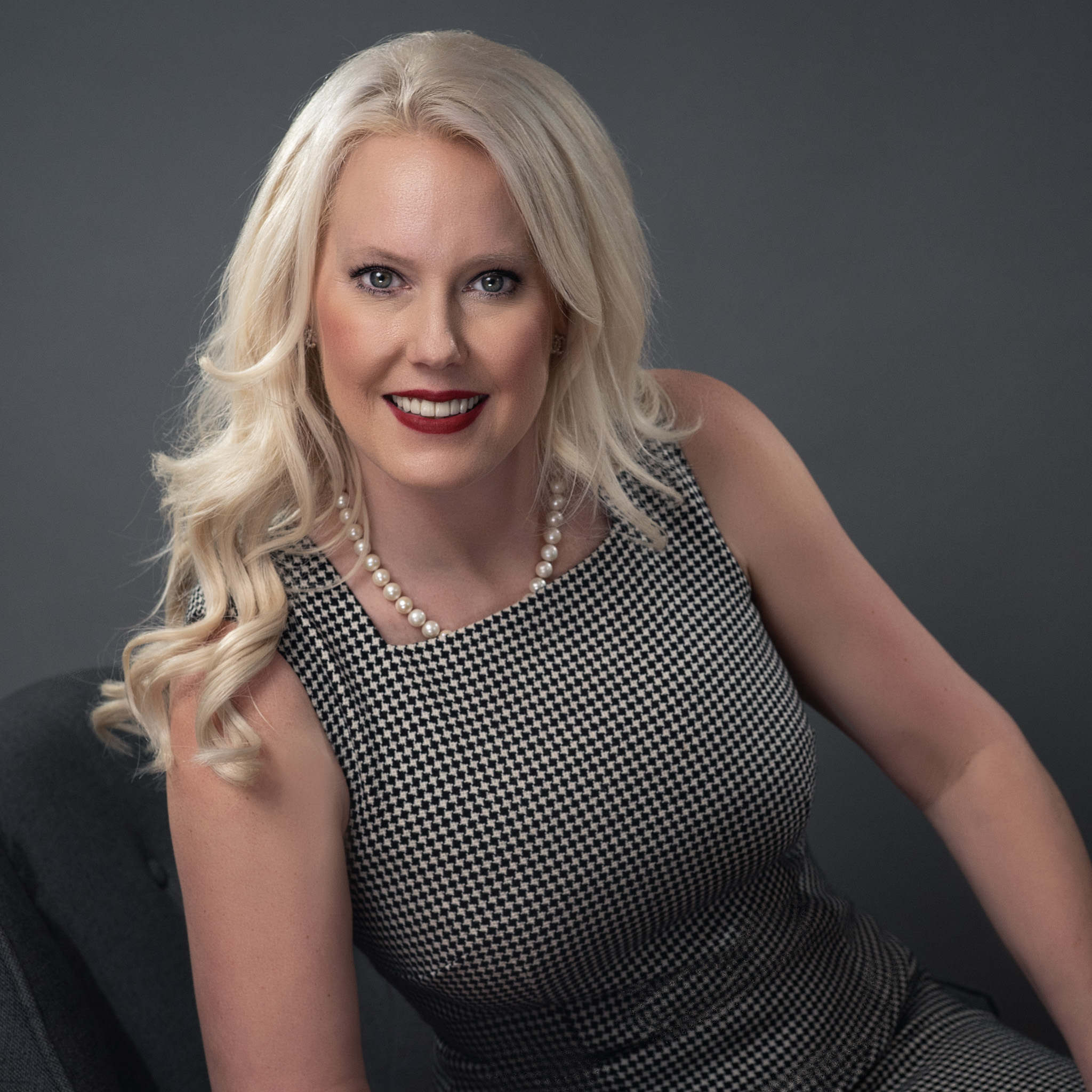 Studio headshot of a luxury female Charleston realtor in soft tones, smiling gently