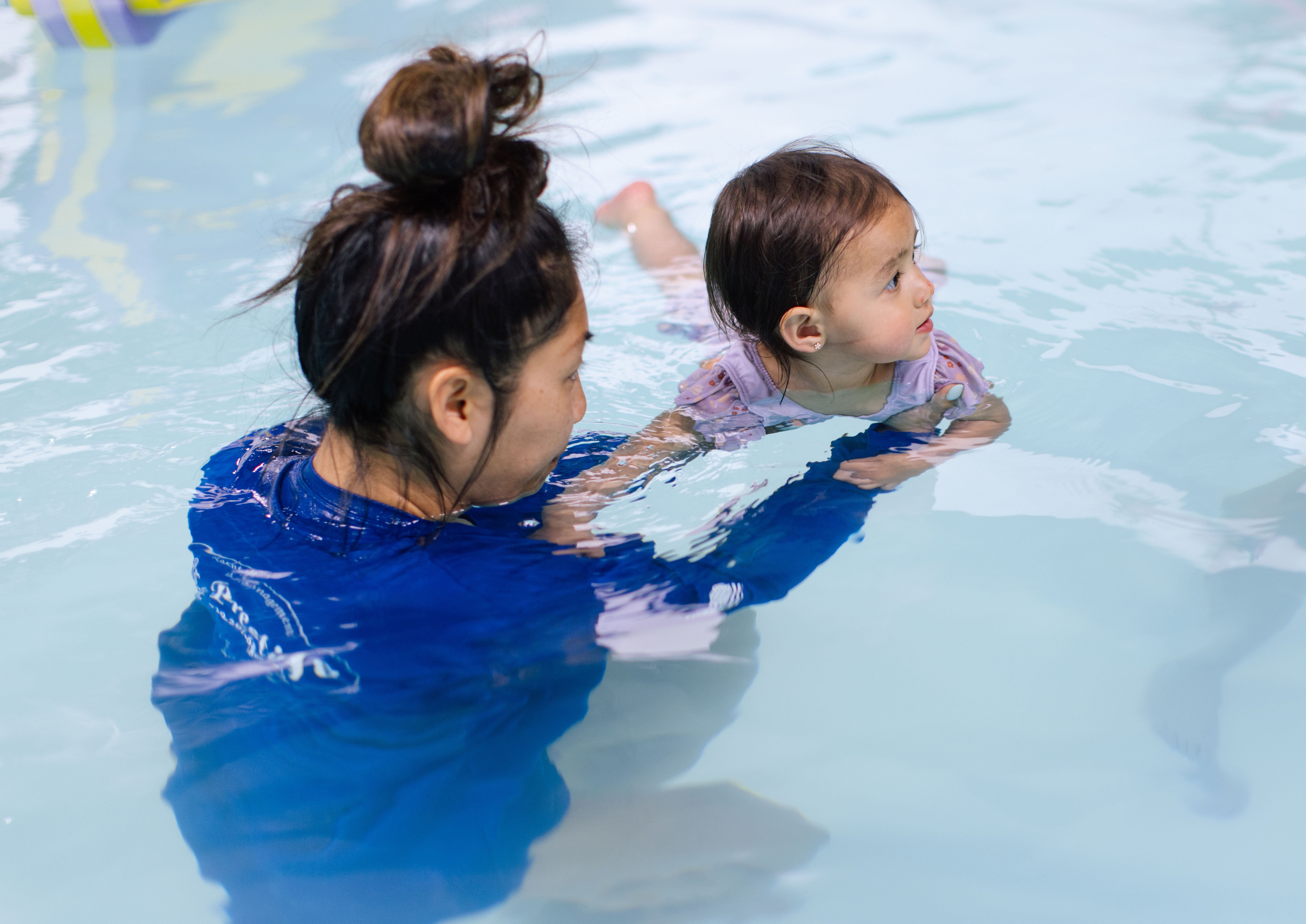 Instructor supports a toddler practicing supported floating