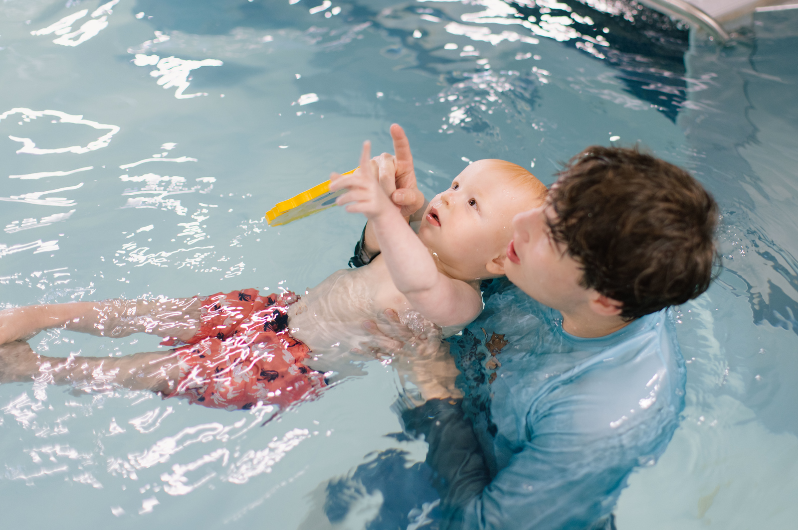 Parent in the water with baby and older siblings during class