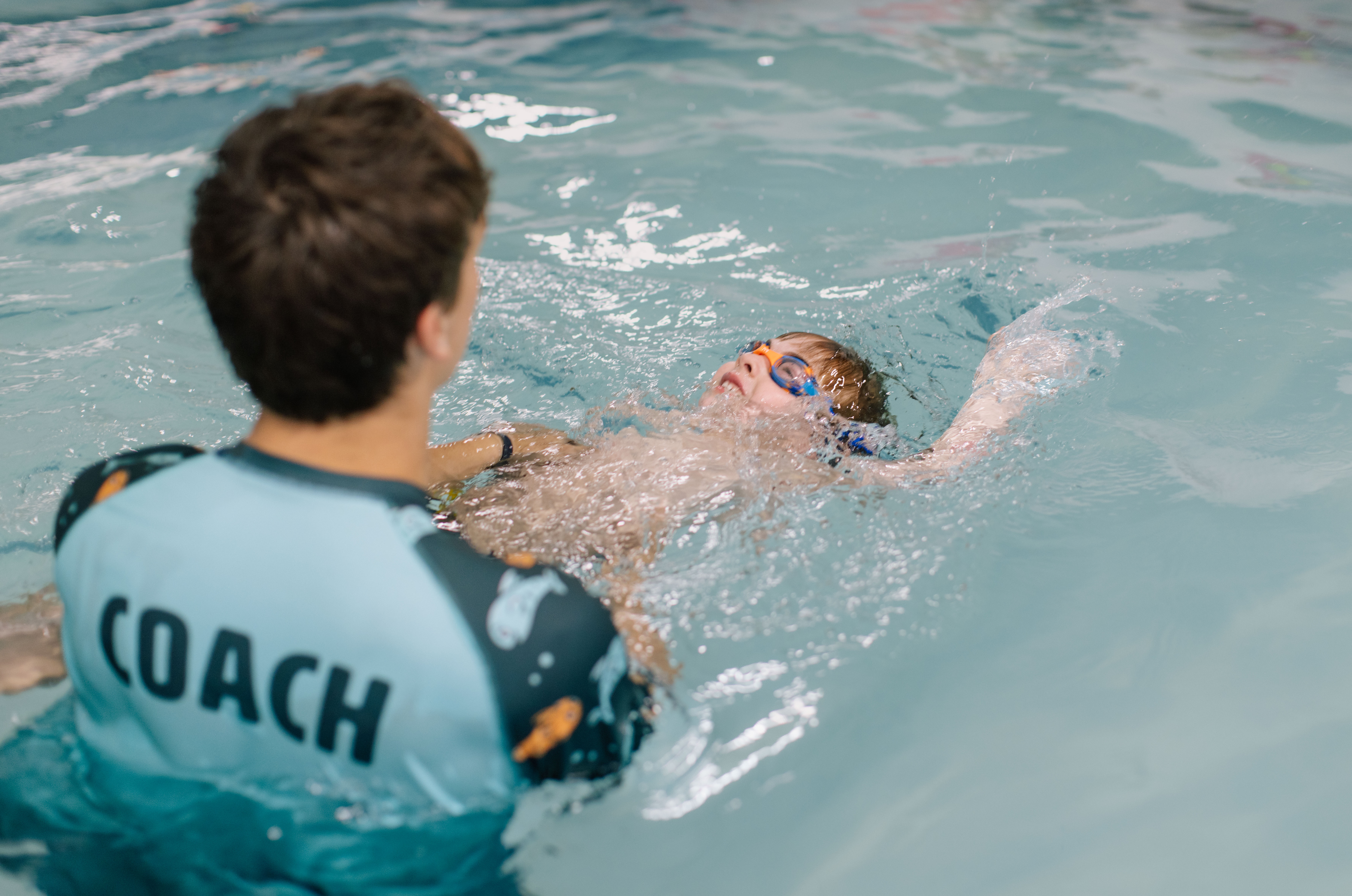 Advanced student practicing backstroke with coach supervision