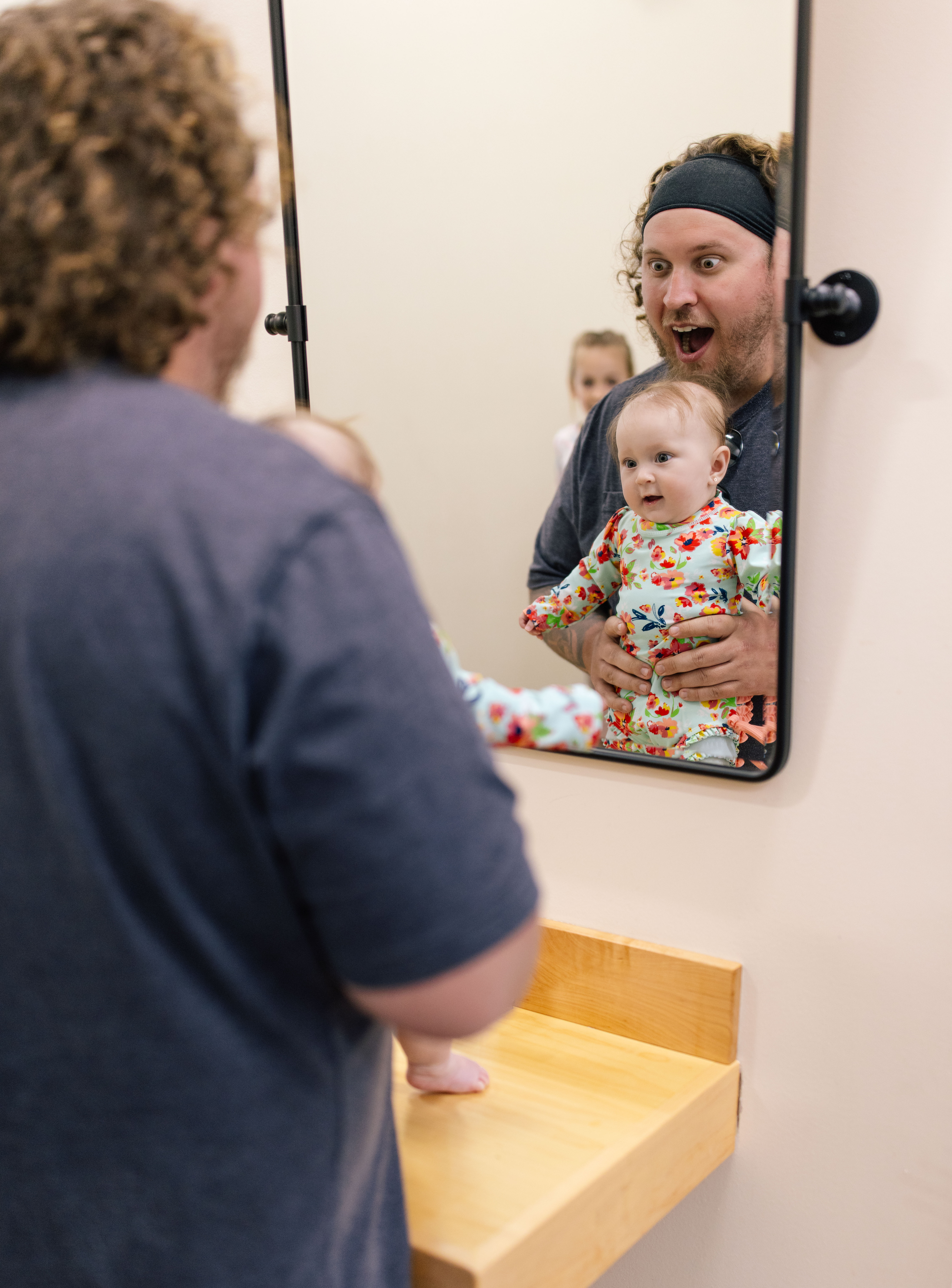 Dad playing peekaboo with his baby in the family changing area mirror