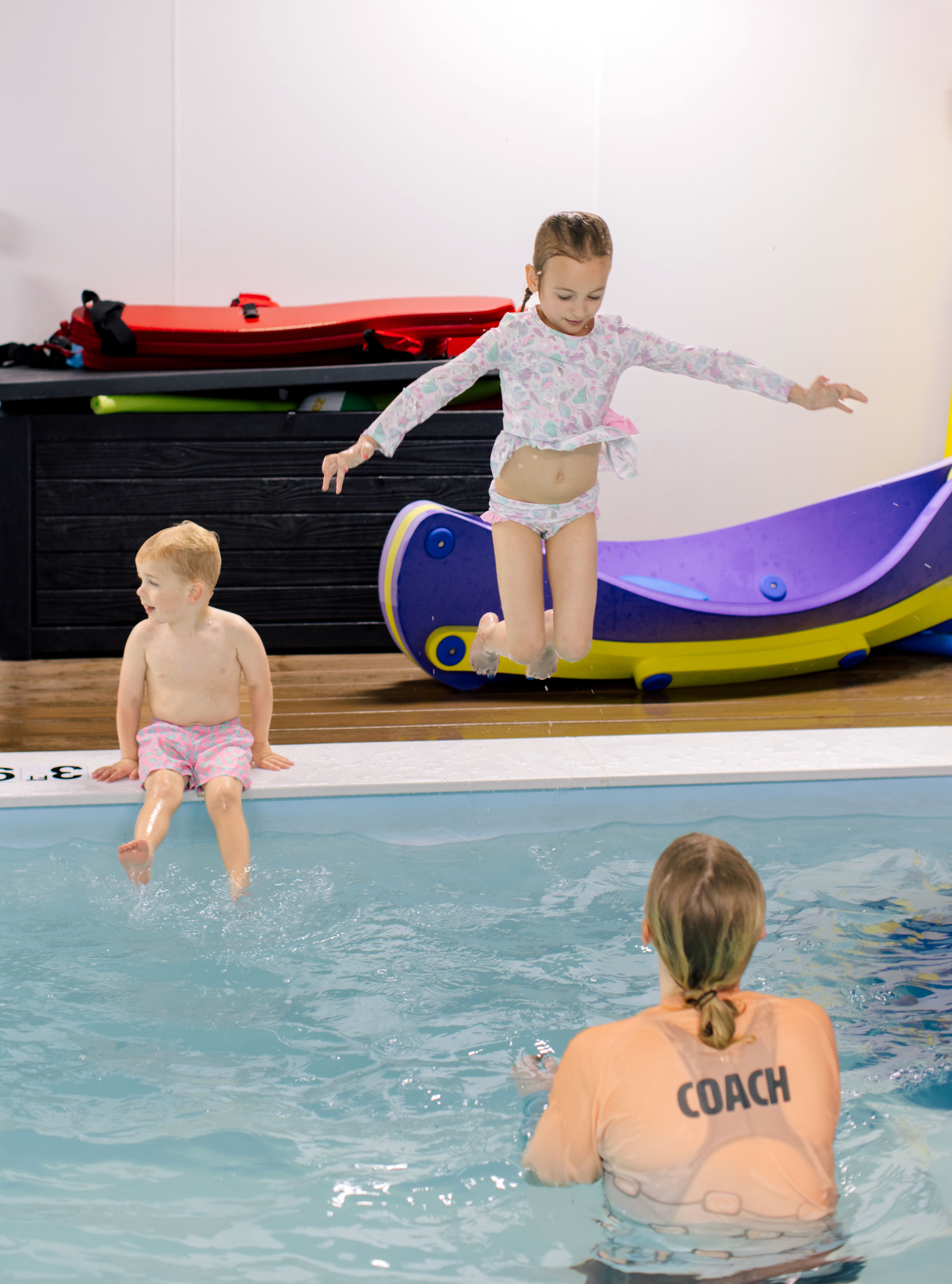 Girl leaping off a foam slide into the pool