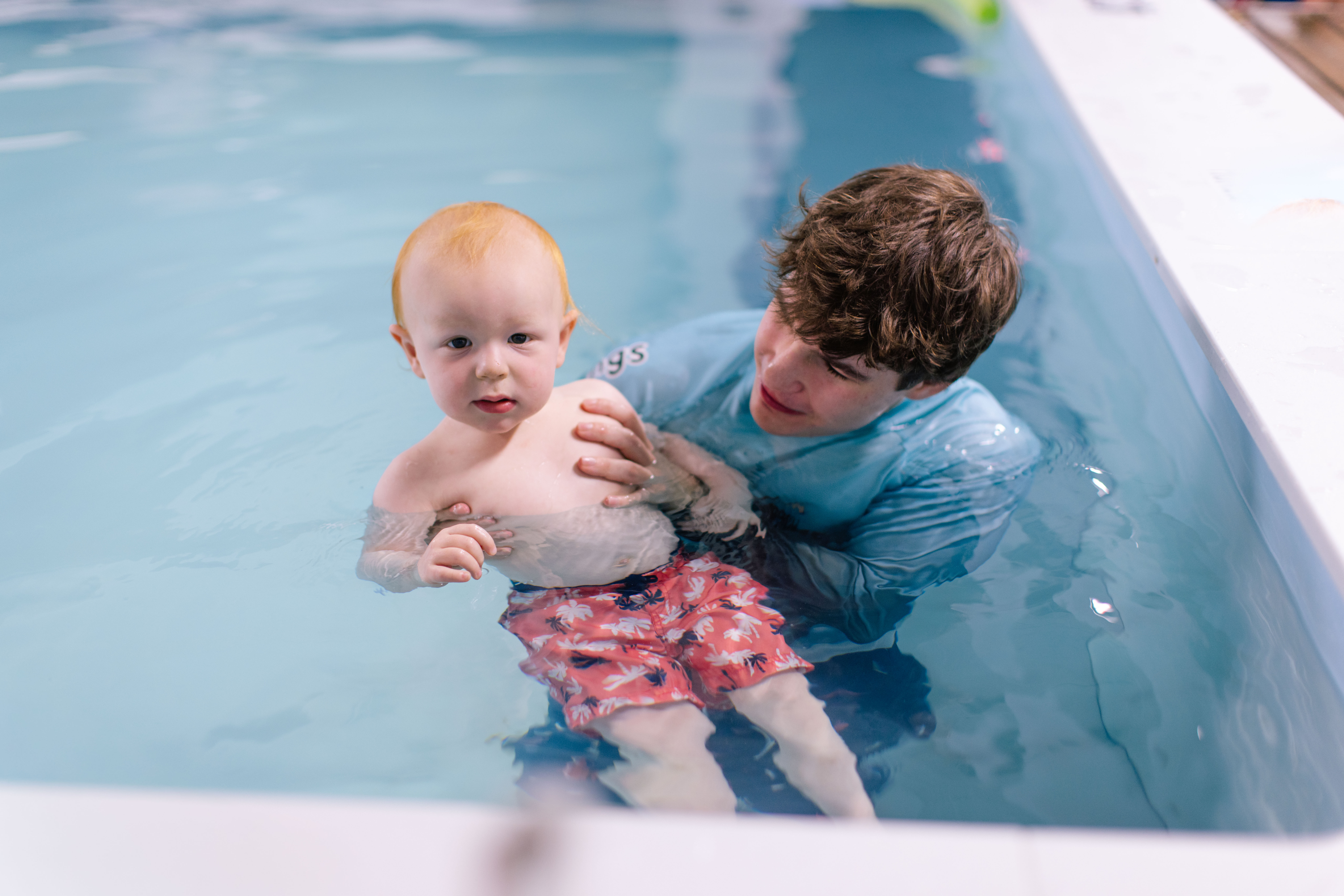 Coach grinning at a baby during their first-time-in-the-water lesson