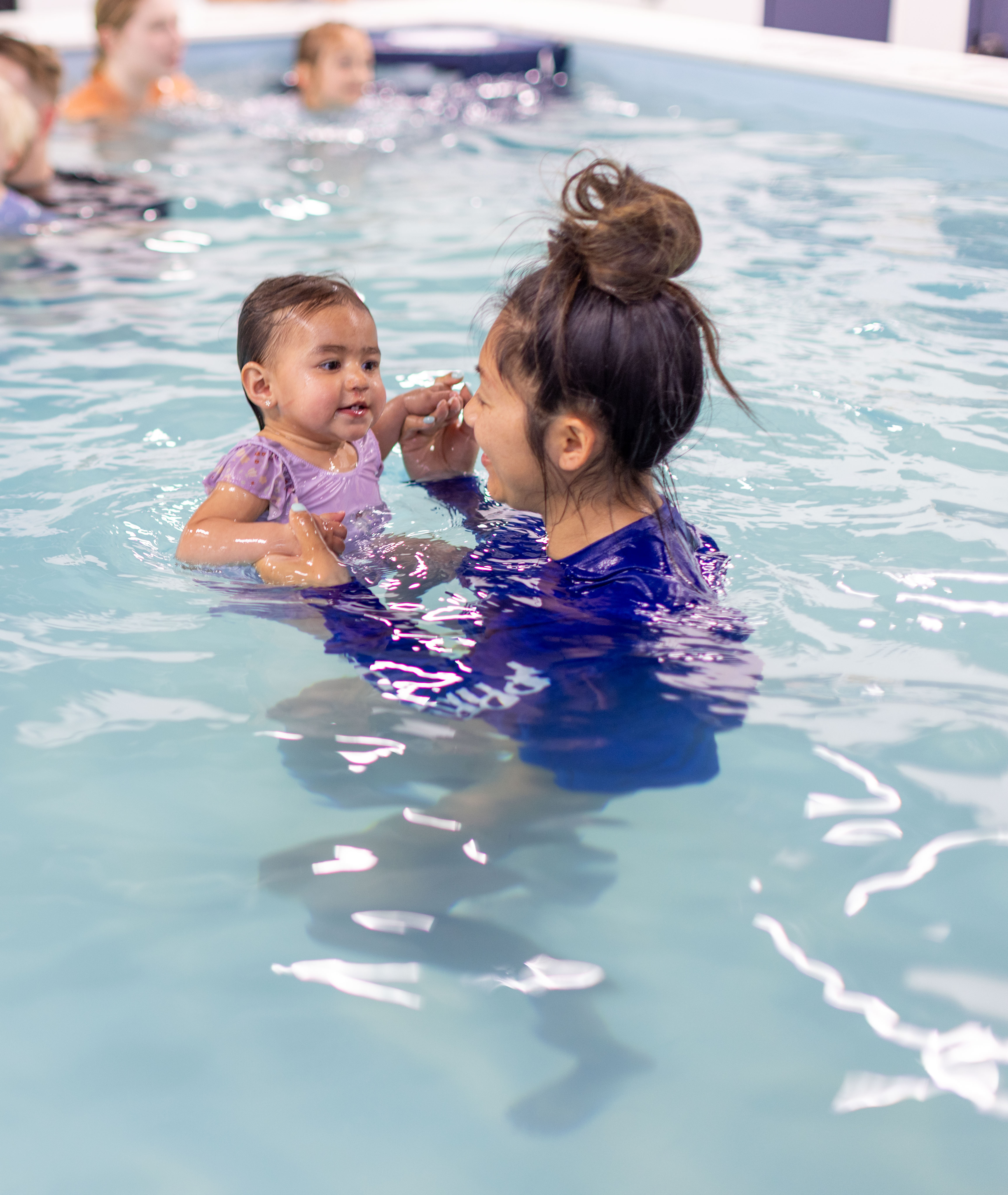 Instructor touches fingers with a toddler girl in an eye-to-eye connection moment